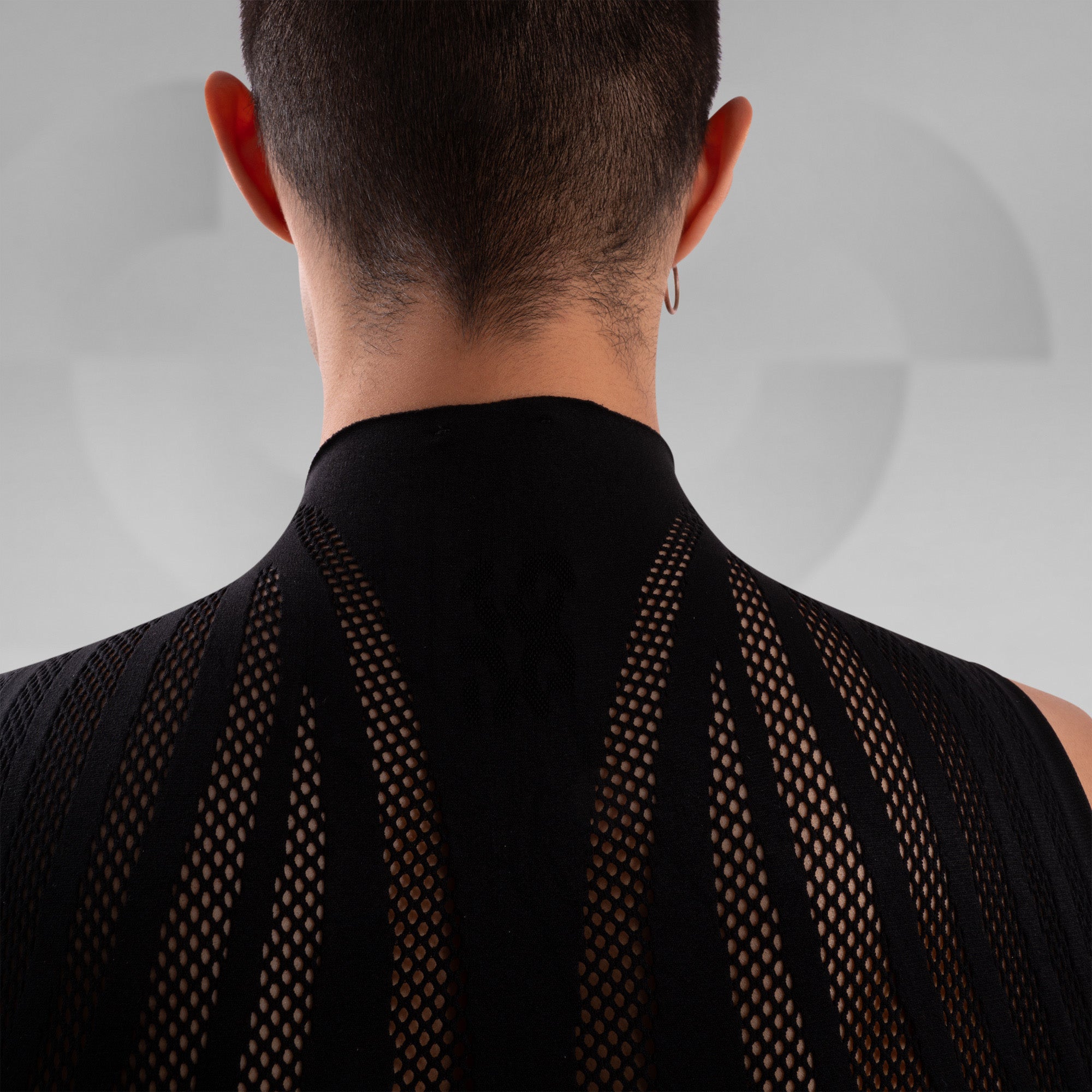 Person wearing a black sleeveless top with mesh back design on a plain background