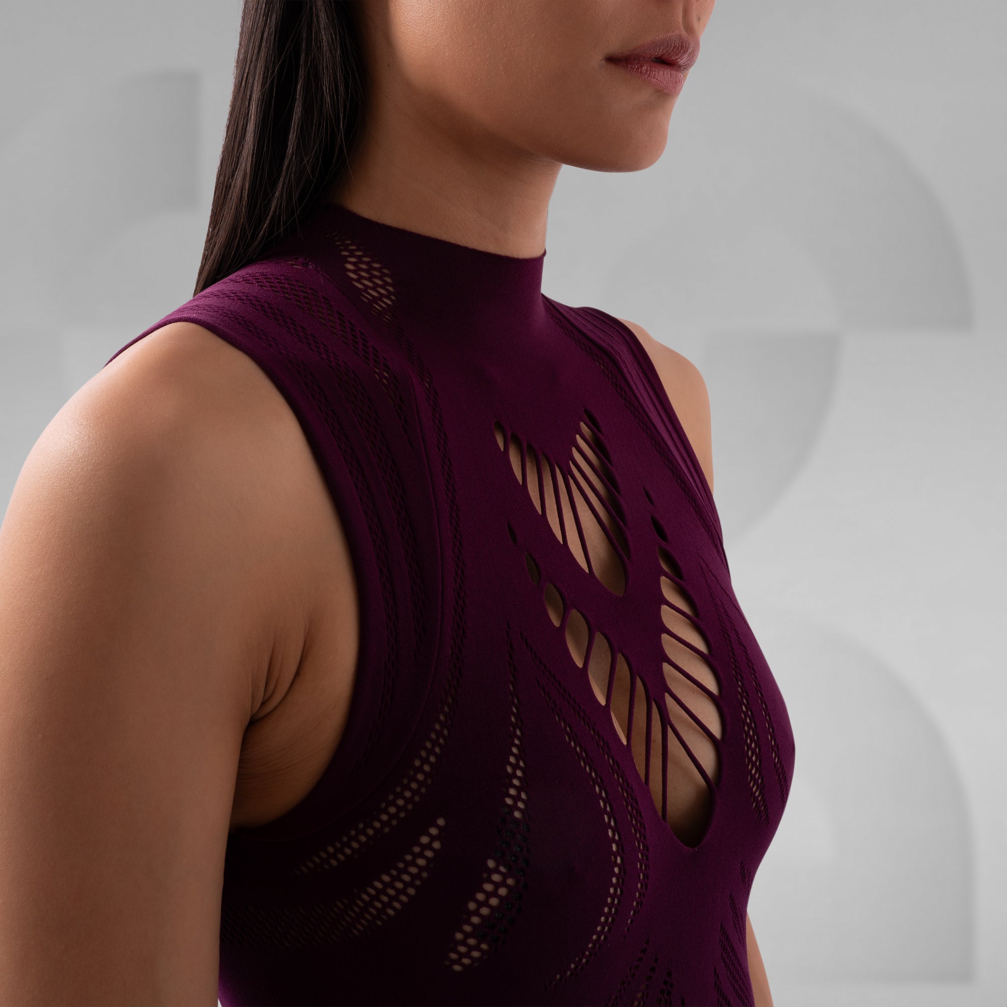 Close-up of a person wearing a dark purple sleeveless top with intricate cut-out design.