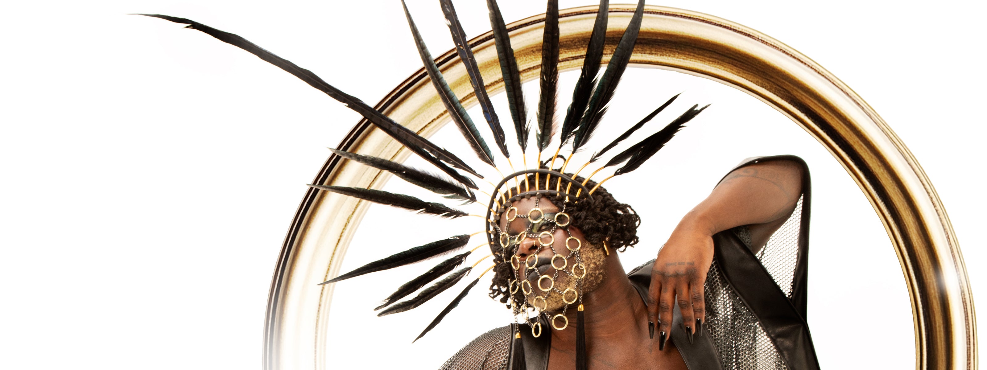 ashing male model showcases a stunning headpiece adorned with flowing, golden feathers that catch the light beautifully. This eye-catching accessory is perfect for festivals or nightclubs, adding a touch of vibrant flair and charisma to any ensemble.