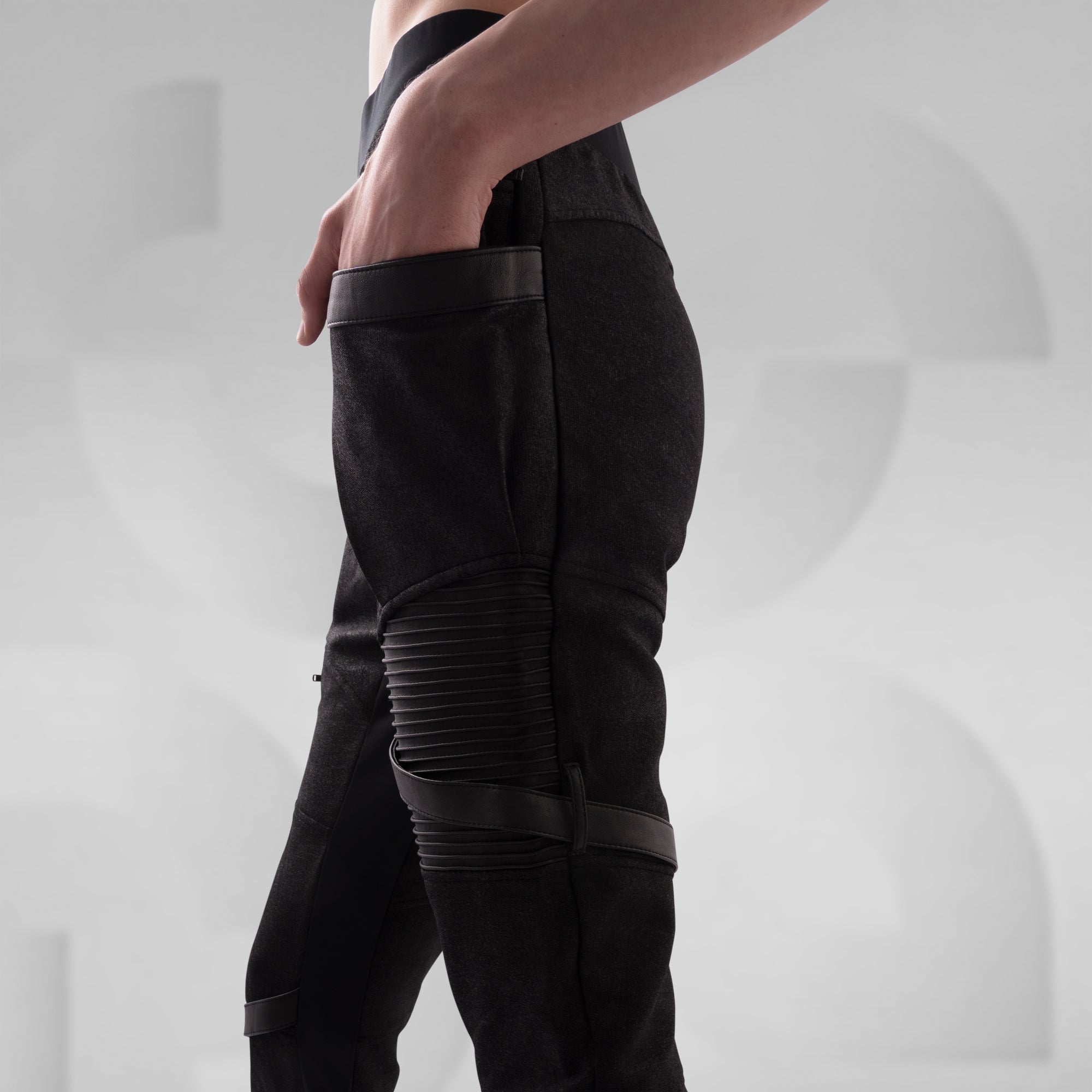 Black pants with zippers and straps on a plain background