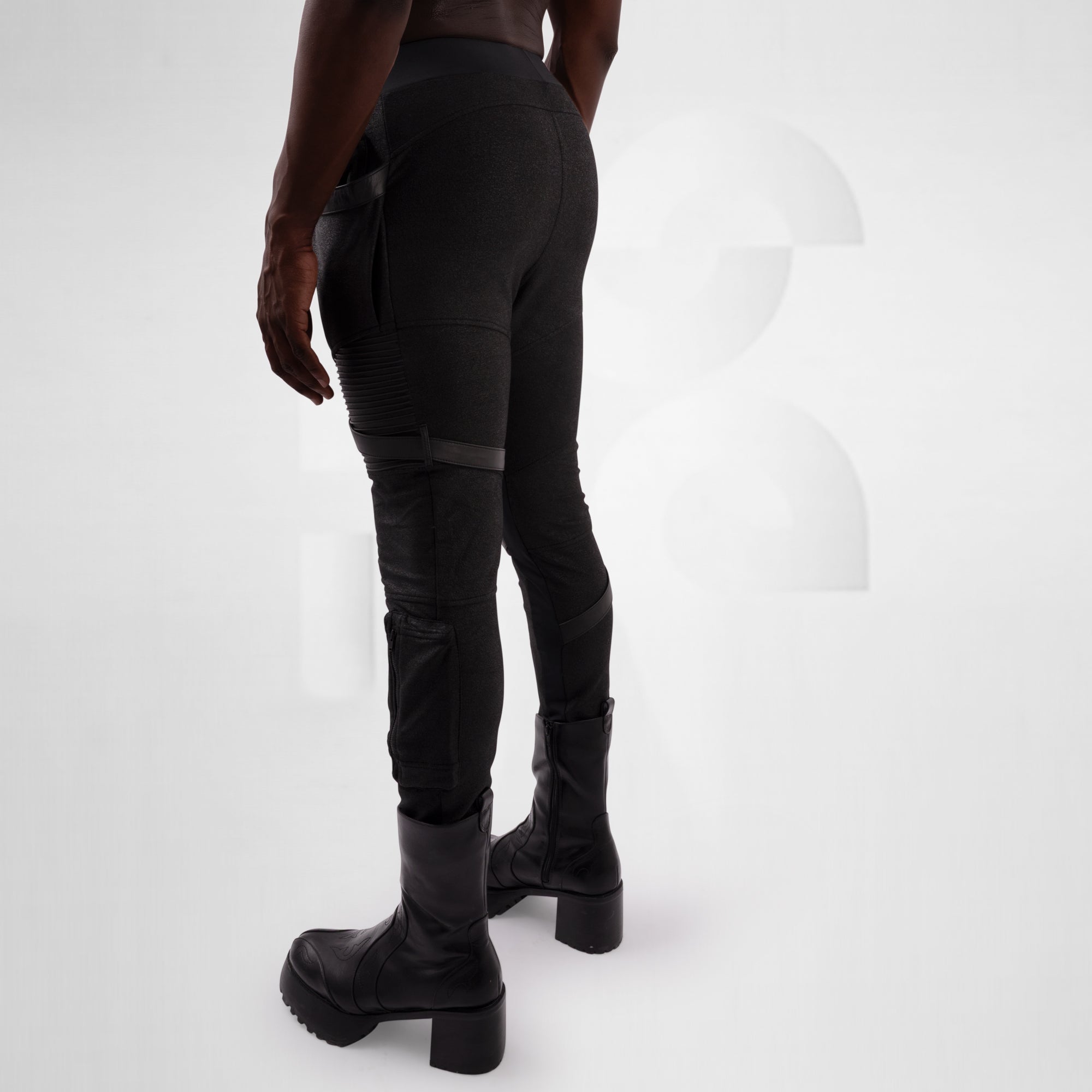 Person wearing black pants and boots on a white background