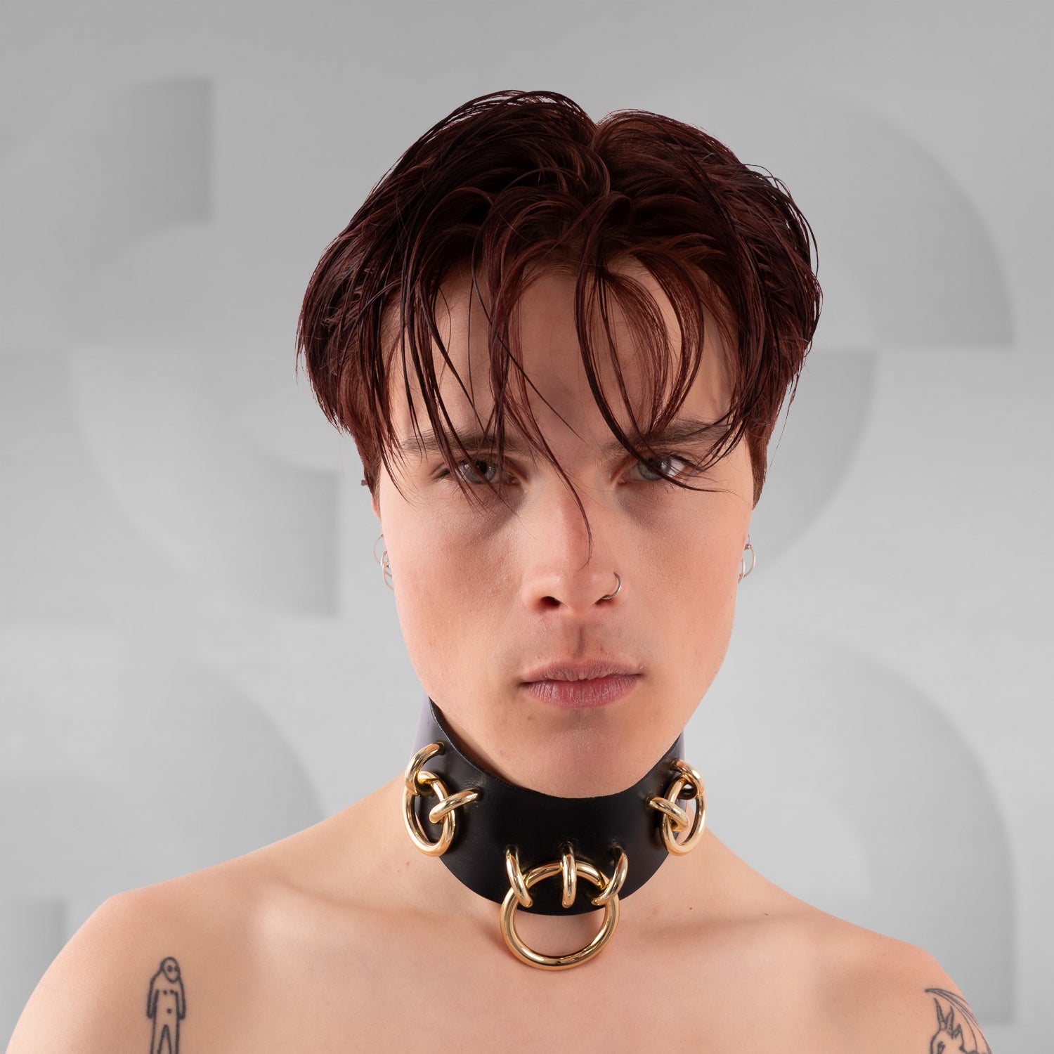 Person wearing a gold and black choker necklace on a gray background