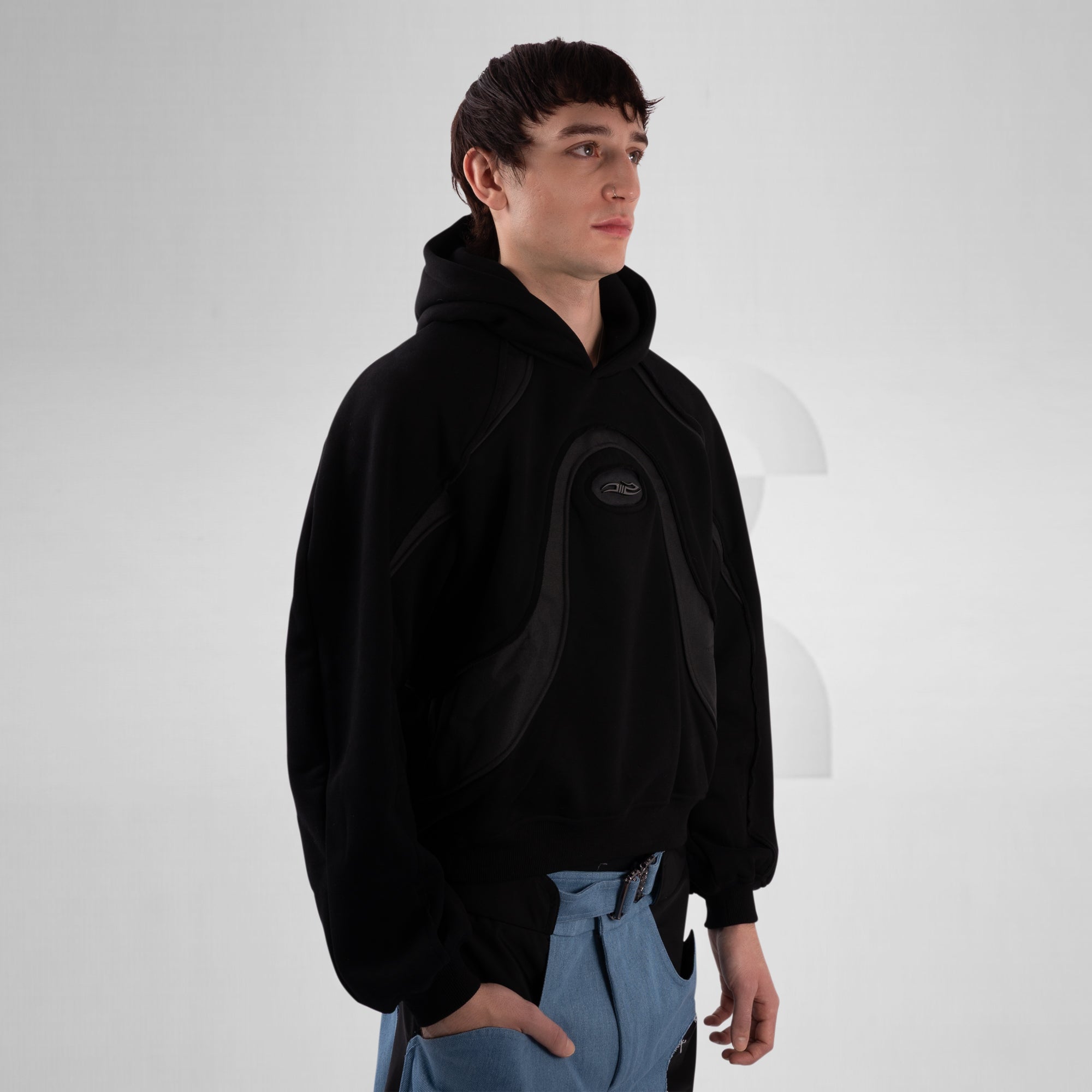 Person wearing a black hoodie with a logo on a white background