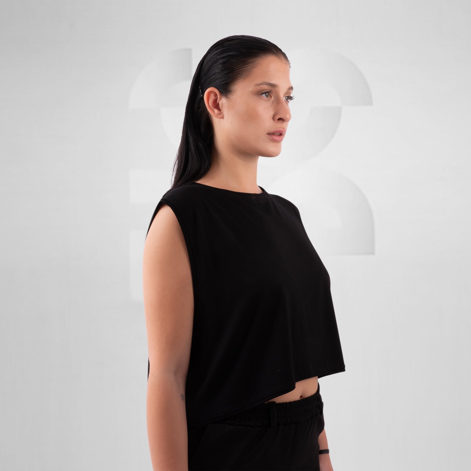 Woman wearing a black sleeveless top against a white background