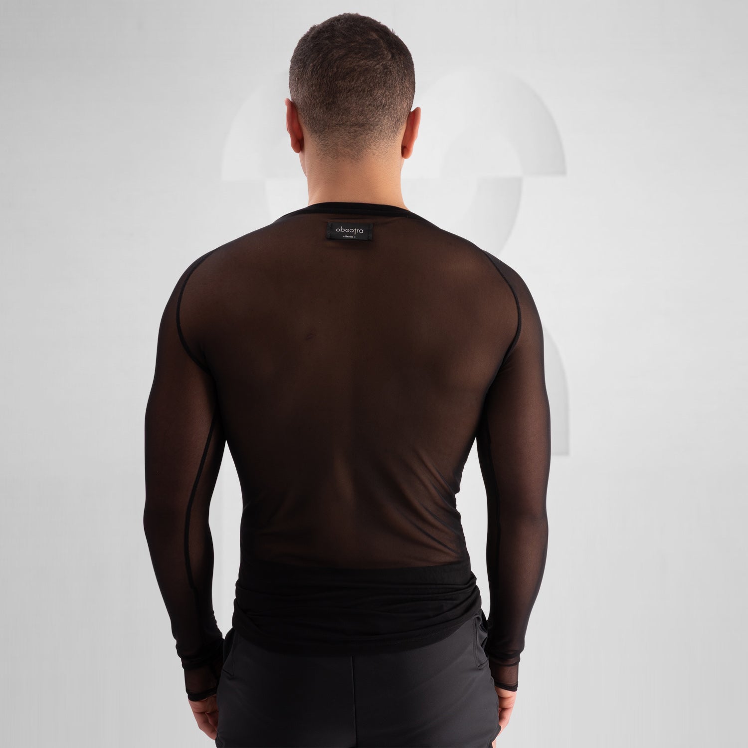 Model wearing a bold, futuristic black sheer long-sleeve top with a high neckline, paired with black cut-out shorts. The look is completed with a statement metallic choker and nipple pasties, creating an edgy, avant-garde aesthetic. Perfect for techno, festival, and alternative fashion