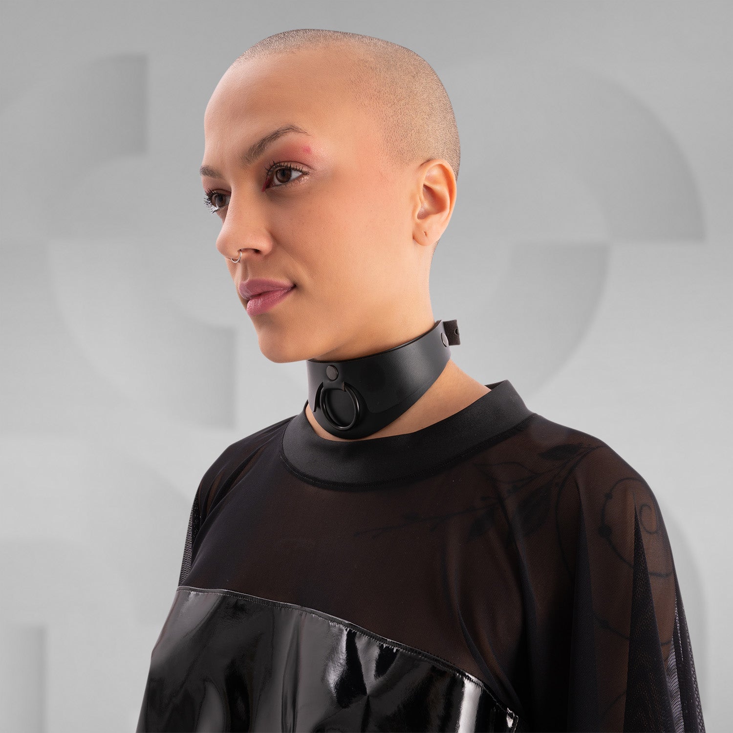 The image features a person wearing a striking outfit that combines a black, glossy top with sheer mesh sleeves, creating a bold and modern aesthetic. The top's shiny material adds an eye-catching element, while the coordinating shorts feature angular holographic designs that reflect light beautifully. This look embodies a dynamic blend of avant-garde fashion and street style, perfect for making a statement.