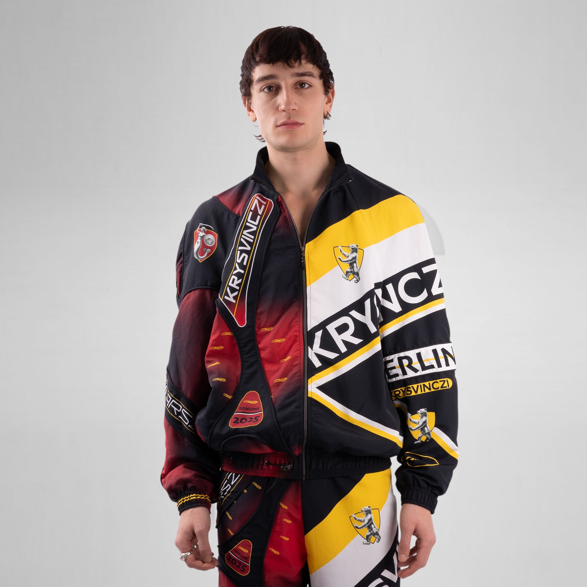 Person wearing a colorful jacket with brand logos on a gray background