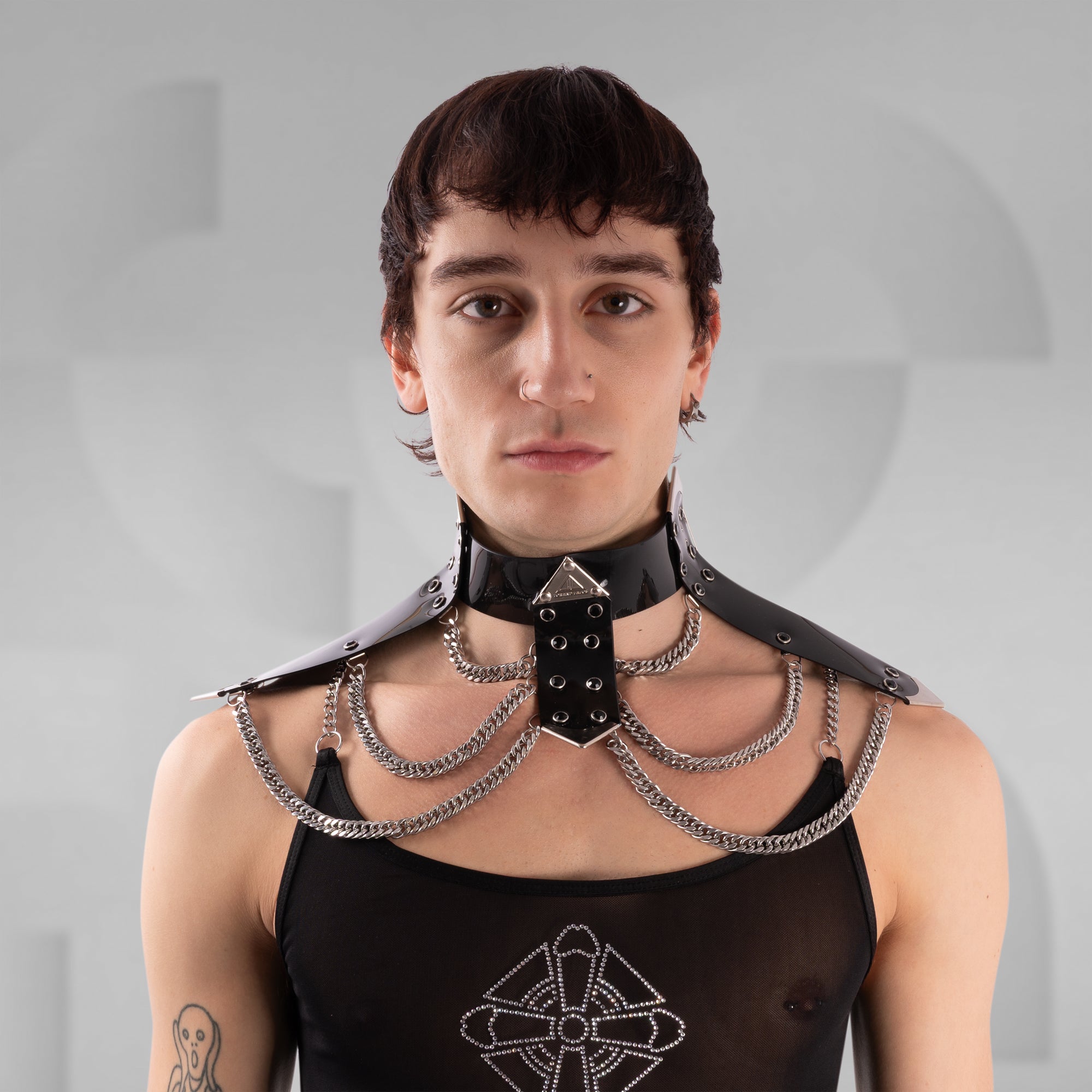 Person wearing a black leather choker with chains on a gray background