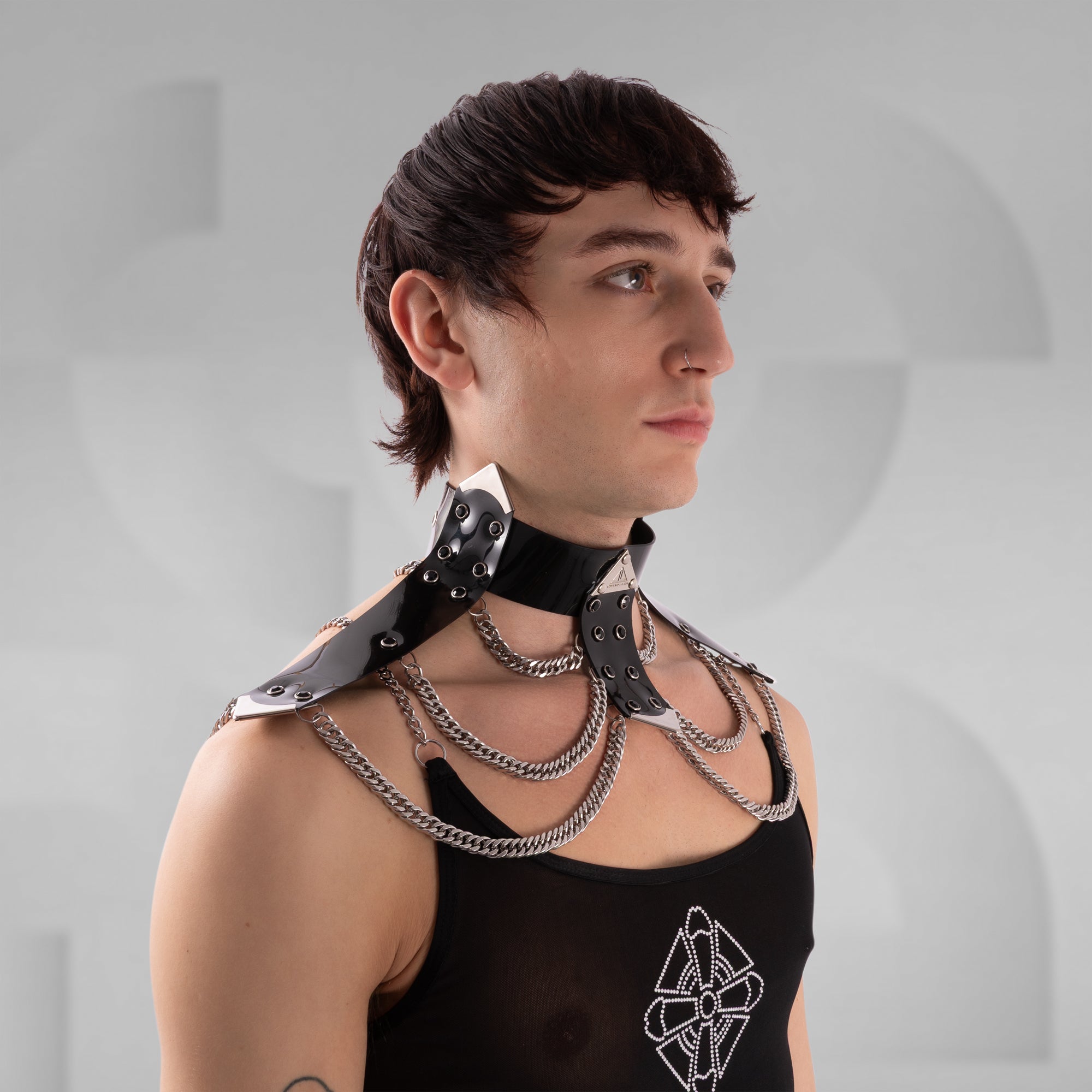 Person wearing a black leather collar with chains on a gray background