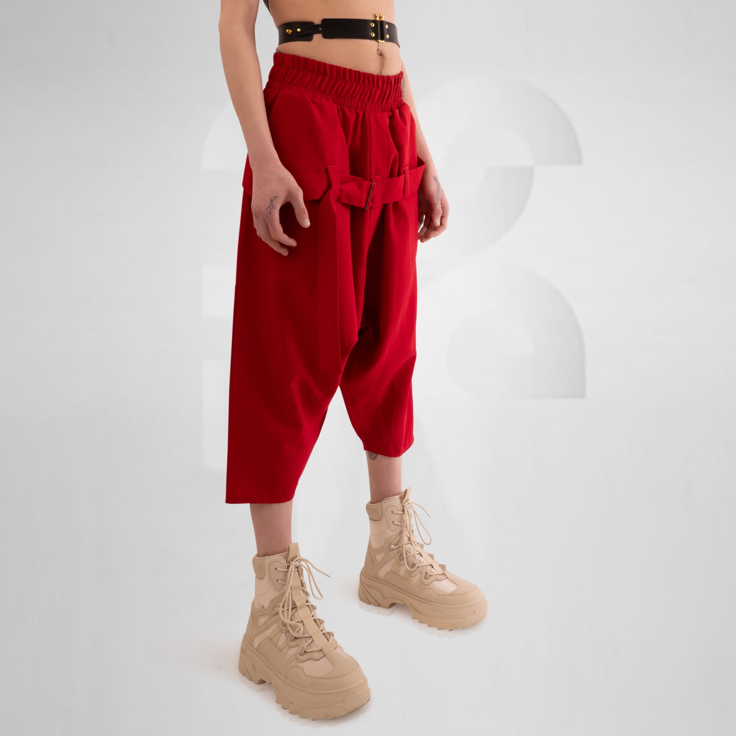 The Wide Trousers with Straps Mixed from This is Fred showcase a bold red hue and an avant-garde design that commands attention. The adjustable straps not only lend a unique twist to the silhouette but also allow for a customizable fit. Practical pockets enhance functionality, making these trousers the perfect fusion of style and utility. Paired with chunky boots, they create a striking outfit that is both contemporary and creative, ideal for expressing your unique fashion sense.