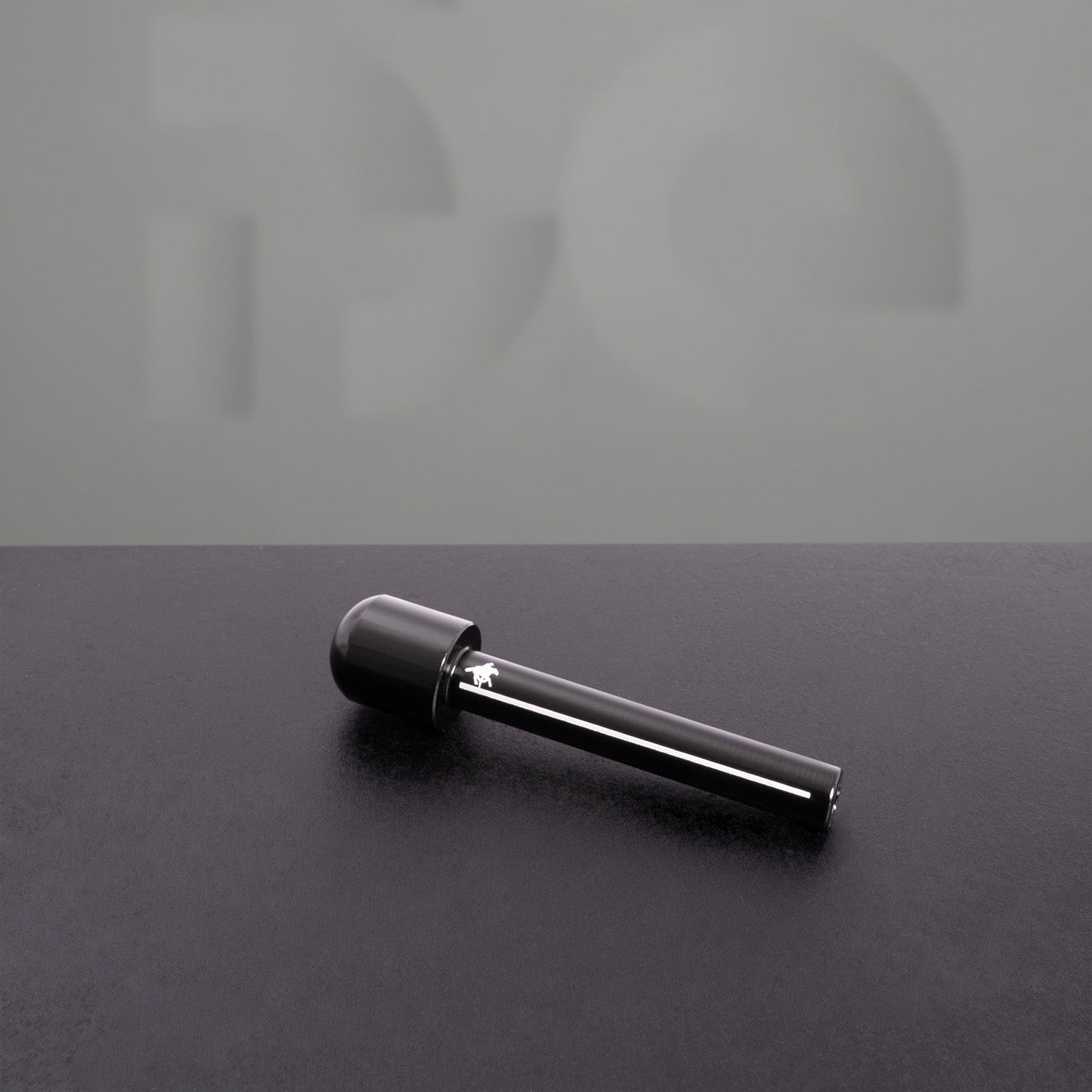 Elegant black dropper with a glossy finish lying on a dark textured surface, reflecting light. The minimalistic background features a subtle embossed design, adding a modern and sophisticated aesthetic.