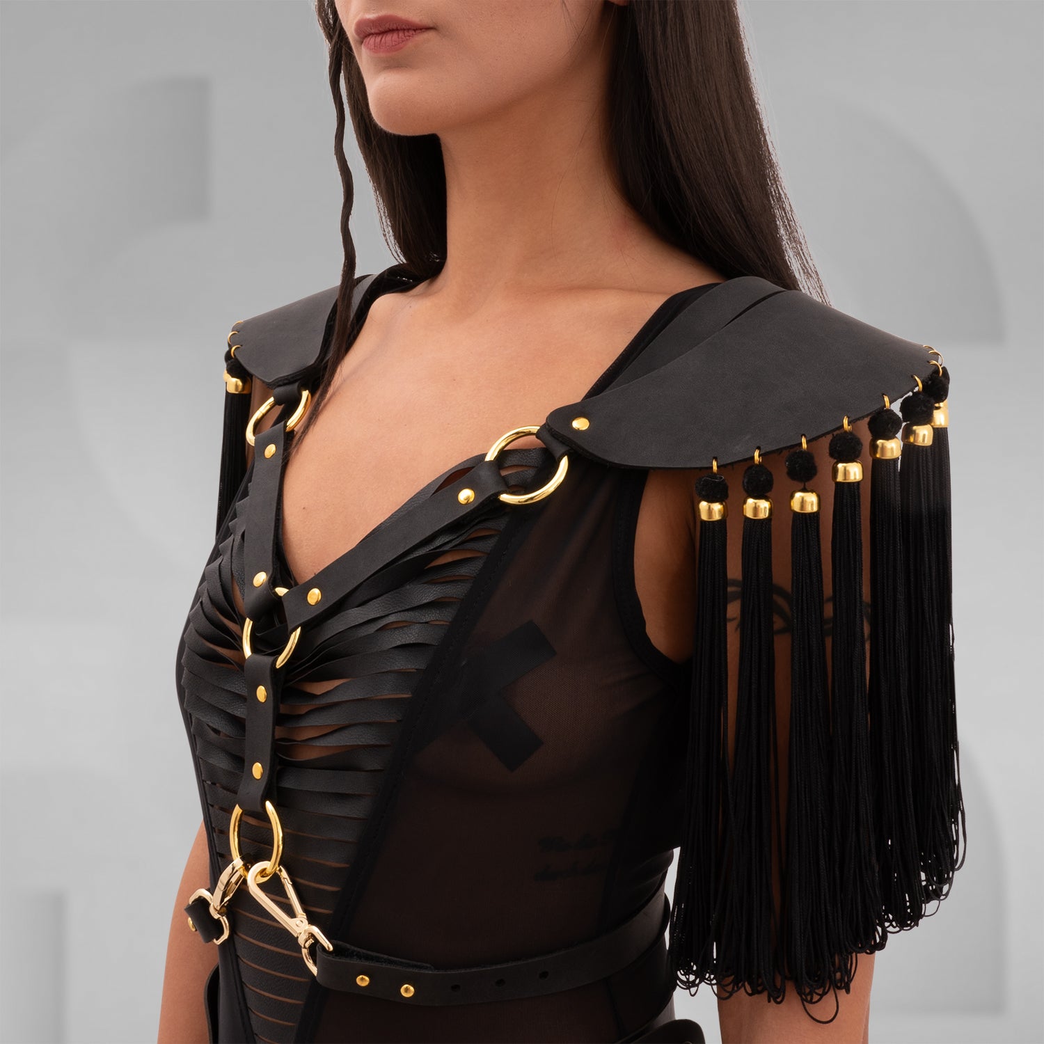 Vegan leather shoulder harness with flowing tassels and gold bead details, inspired by ancient warriors and celestial aesthetics. Adjustable straps for an empowering, mystical fit.