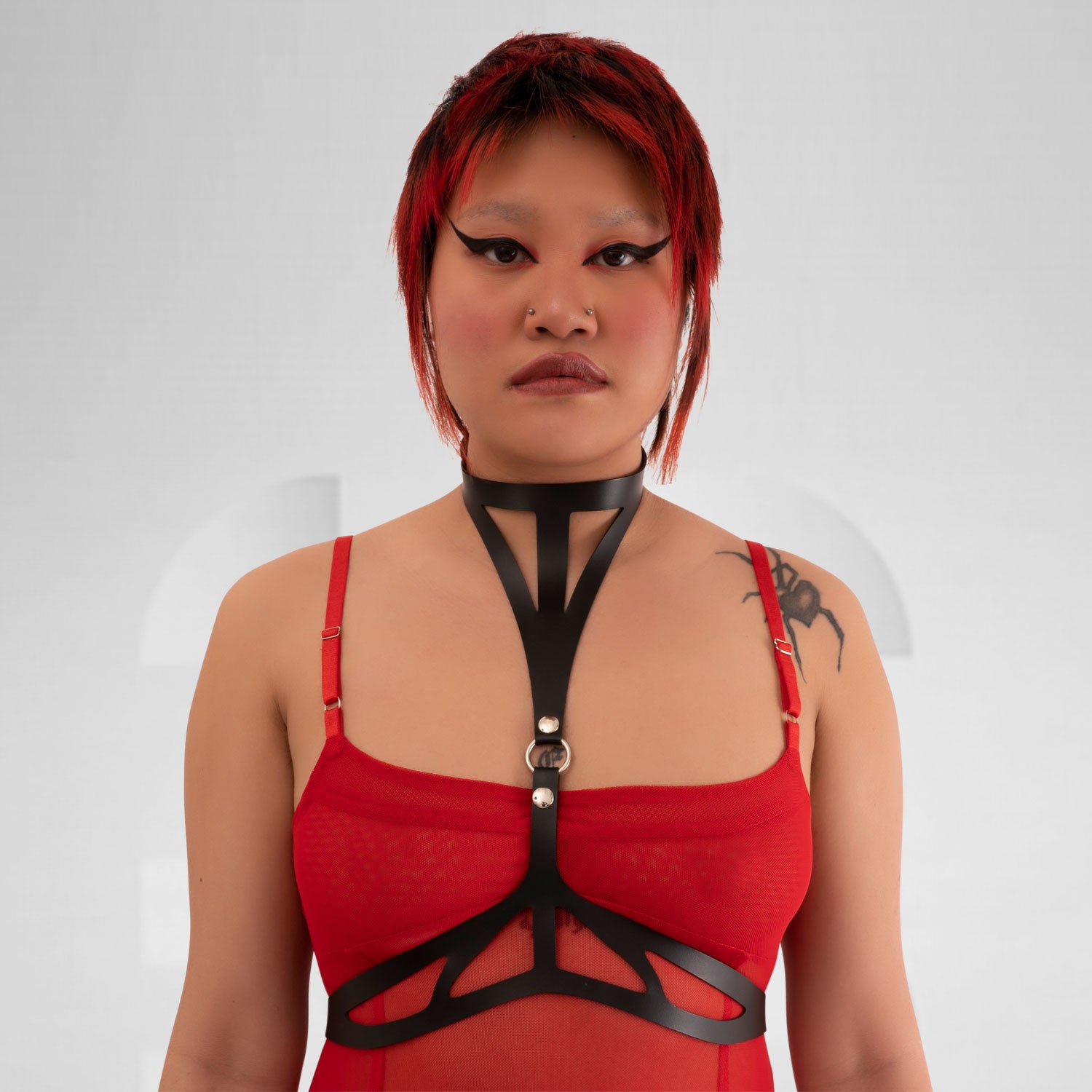 Vegan leather harness sculpting the body in avantgarde clubwear style.