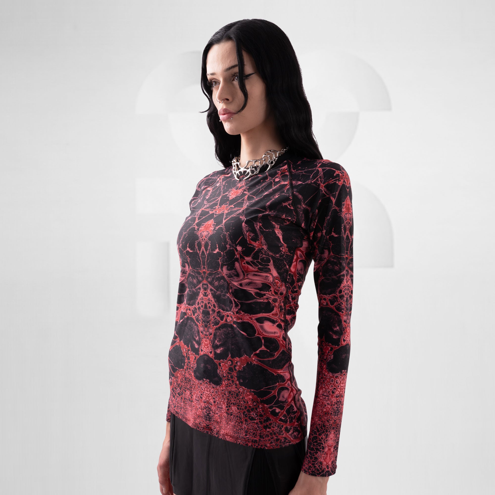 Woman wearing a red and black patterned long-sleeve top on a white background