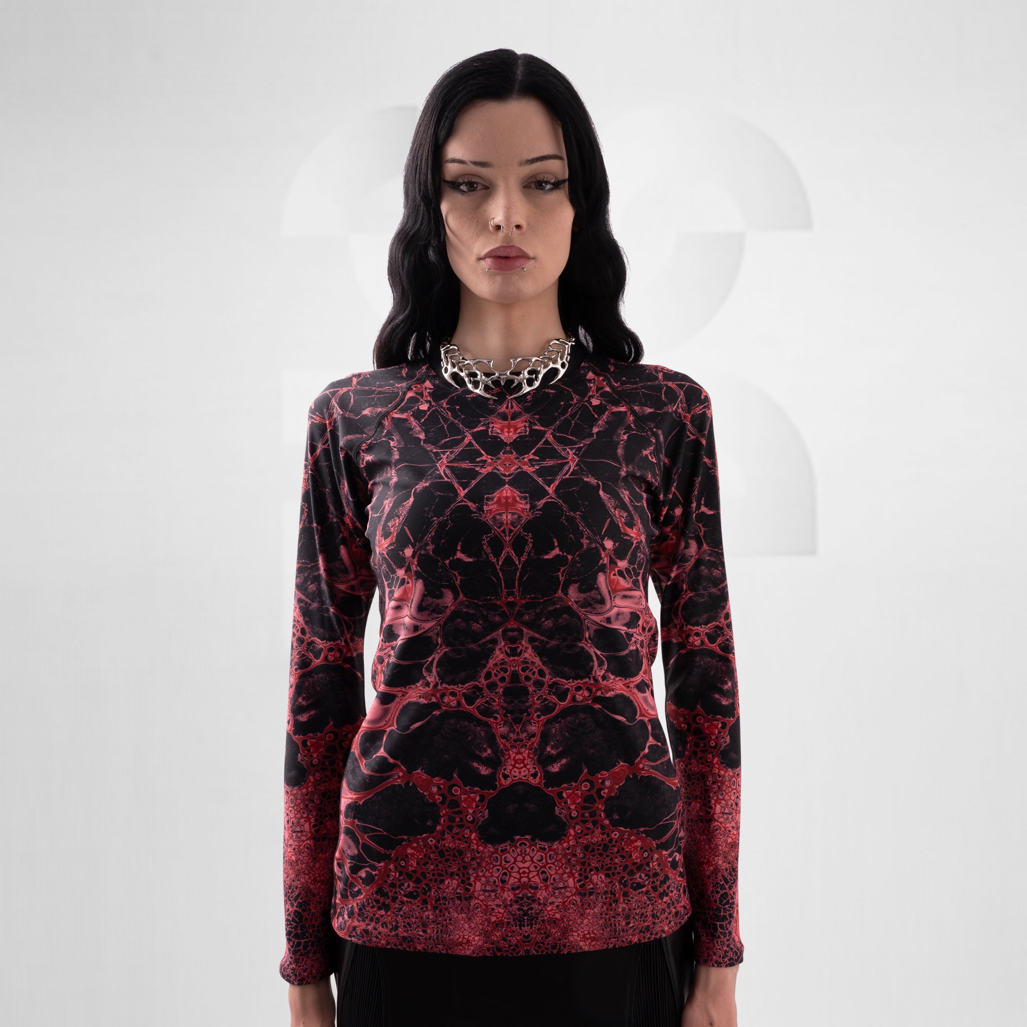 Woman wearing a red and black patterned long-sleeve top on a white background