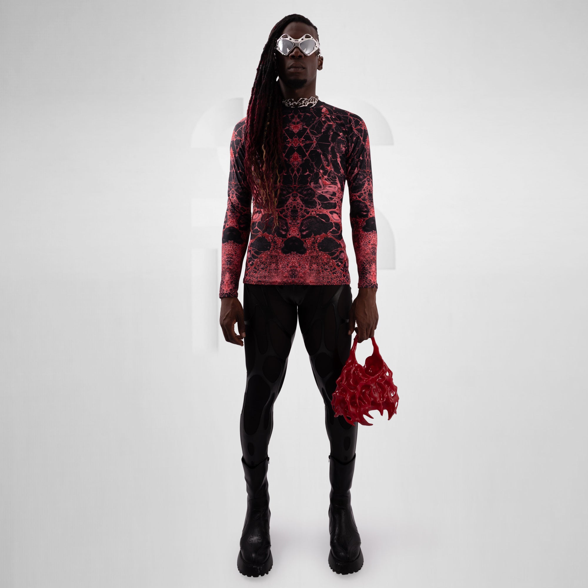 Person wearing a red and black patterned outfit with a matching bag on a white background