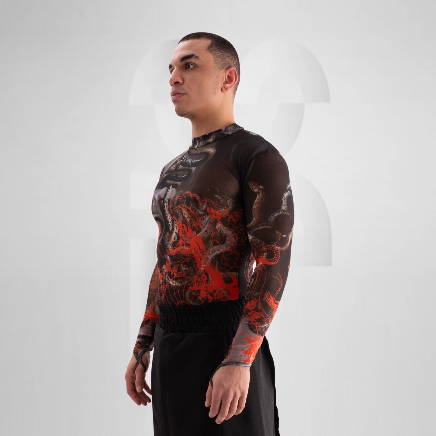 The image showcases a striking outfit featuring a long-sleeve top with an eye-catching design of swirling octopuses in dark hues, accented with vibrant red. The top is complemented by unique metallic neck detailing that adds an edgy flair. Paired with black high-waisted shorts featuring cut-out details, this look exudes confidence and individuality. Ideal for making a statement on the dancefloor or at a fashion-forward event, the ensemble beautifully blends art and style for a captivating appearance.