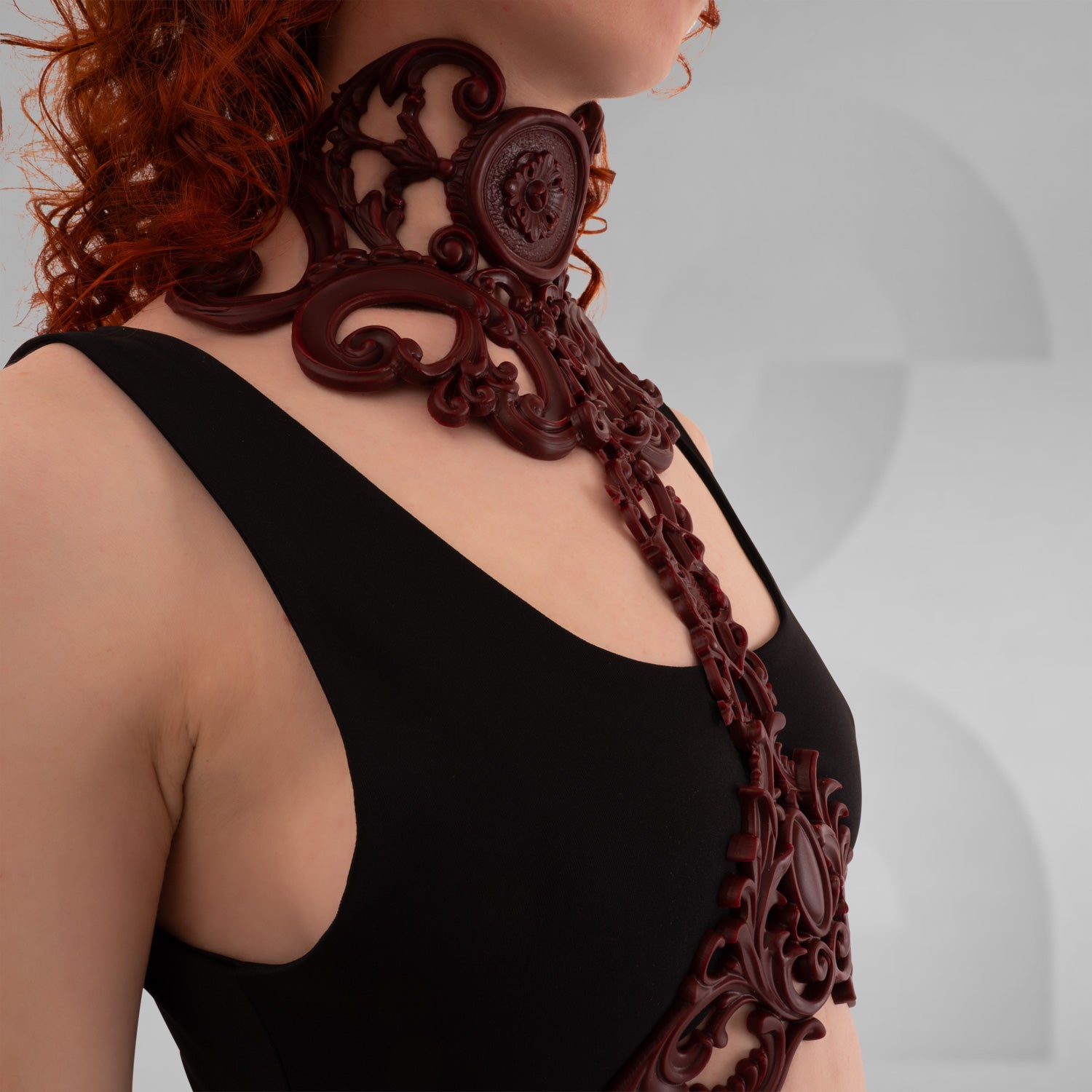 This image showcases a model wearing an elegant dark red harness that features intricate baroque detailing. The harness beautifully frames the model's neckline, combining artistic design with a modern flair. Its bold structure adds a striking element to the outfit, making it an excellent choice for those who embrace avant-garde fashion. Perfect for nightlife events or enhancing a casual look, this piece exudes confidence and sophistication.