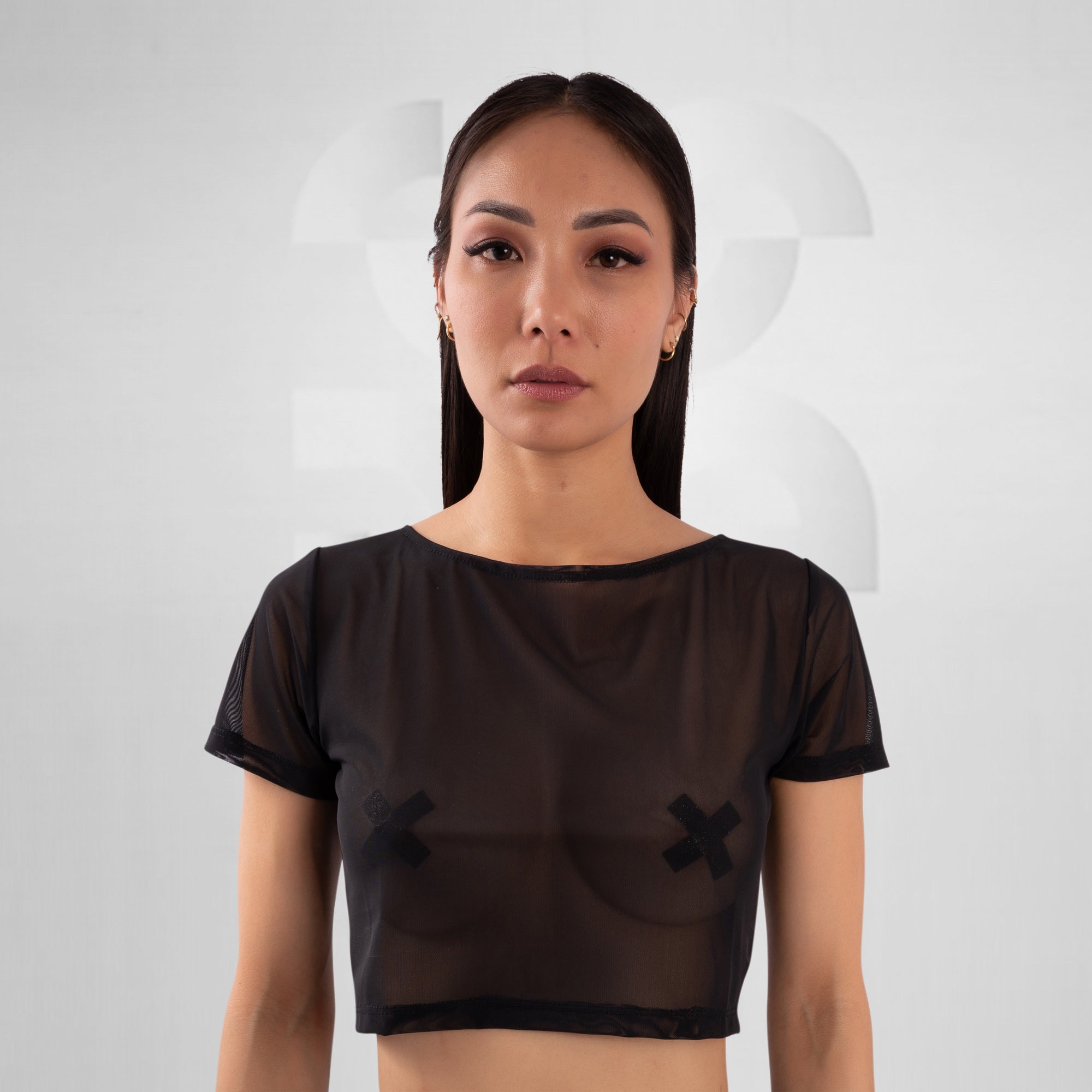Woman wearing a black sheer top with a design on a white background