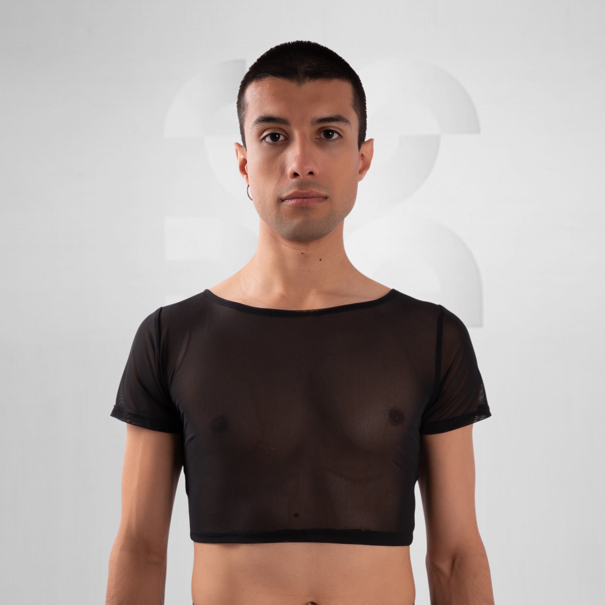 Man wearing a sheer black top against a plain background