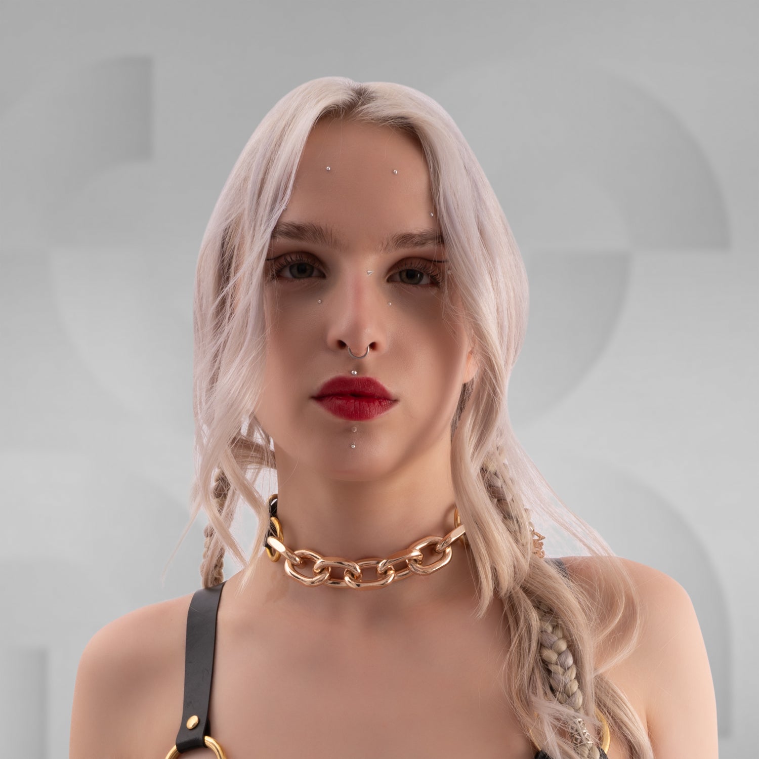 The chain or product shown in the images is a fashion choker and harness made of black material with large gold-colored metal links, rings, and buckles. The design features a combination of chunky links and smaller straps with adjustable buckles, creating an edgy and bold accessory look.