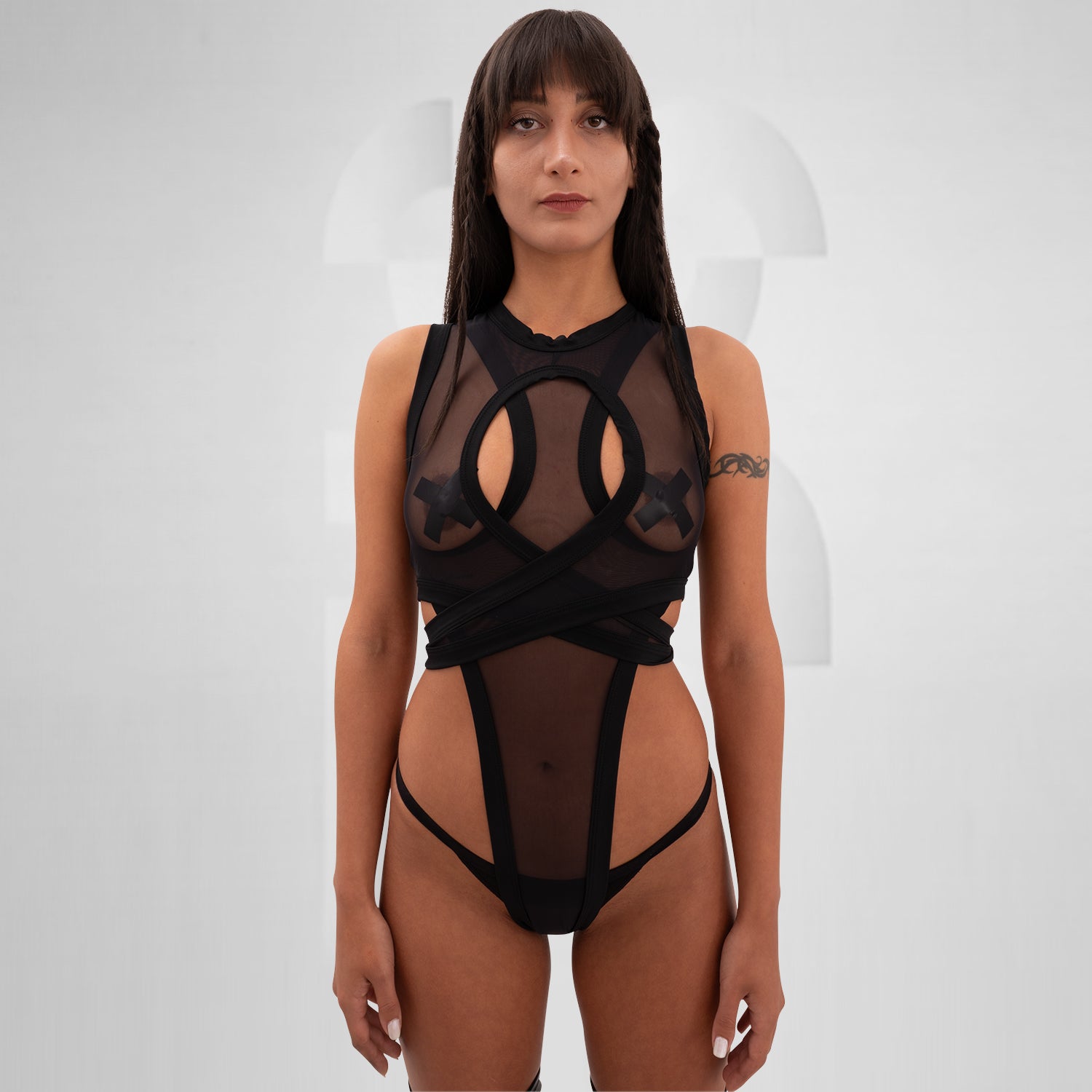The Bound Gender-Neutral Meshed Bodysuit from Berlin designer Nur Hektor is a striking blend of edgy aesthetics and avant-garde fashion. Featuring sheer mesh and bold cut-out details, this unique piece embraces a daring silhouette perfect for festivals and clubwear. The innovative wraparound design not only highlights your figure but also allows for expressive individuality. 