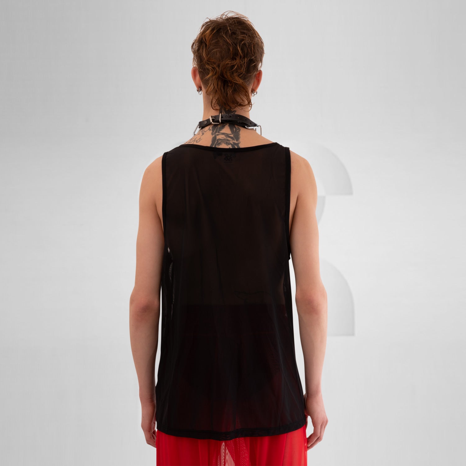 The image features a bold black mesh tank top, designed for the fashion-forward individual looking to make a statement. This sheer piece exudes an edgy vibe, perfect for layering over vibrant ensembles or wearing solo for a striking look. The relaxed fit offers comfort while the unique design highlights individuality, making it ideal for both clubwear and casual outings. Elevate your style and embrace your daring side with this standout top that effortlessly combines modern aesthetics and versatility!