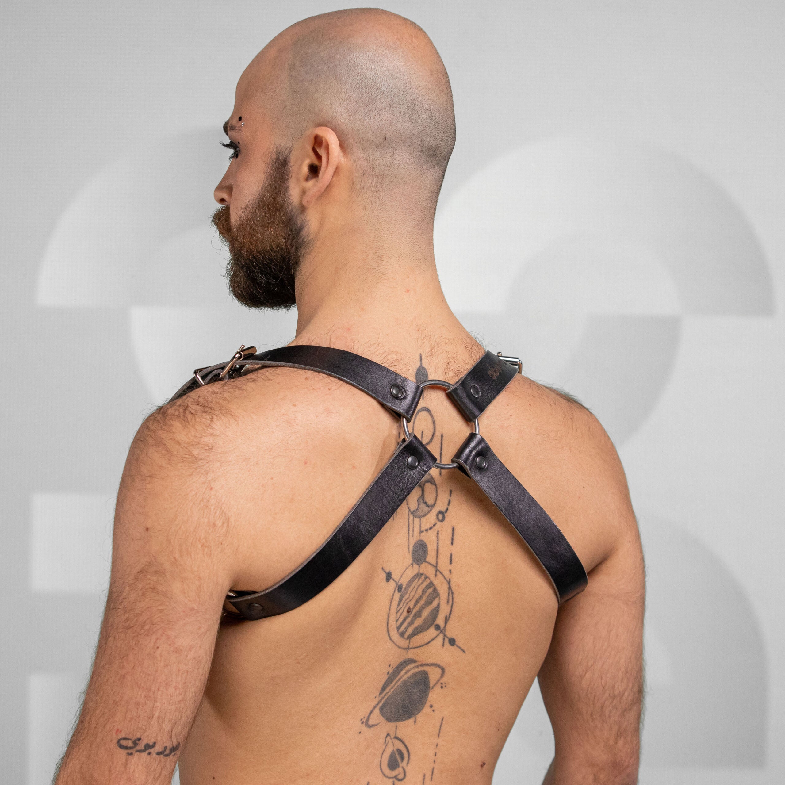 Bold, versatile unisex leather shoulder harness with cross-back design and dual buckles.