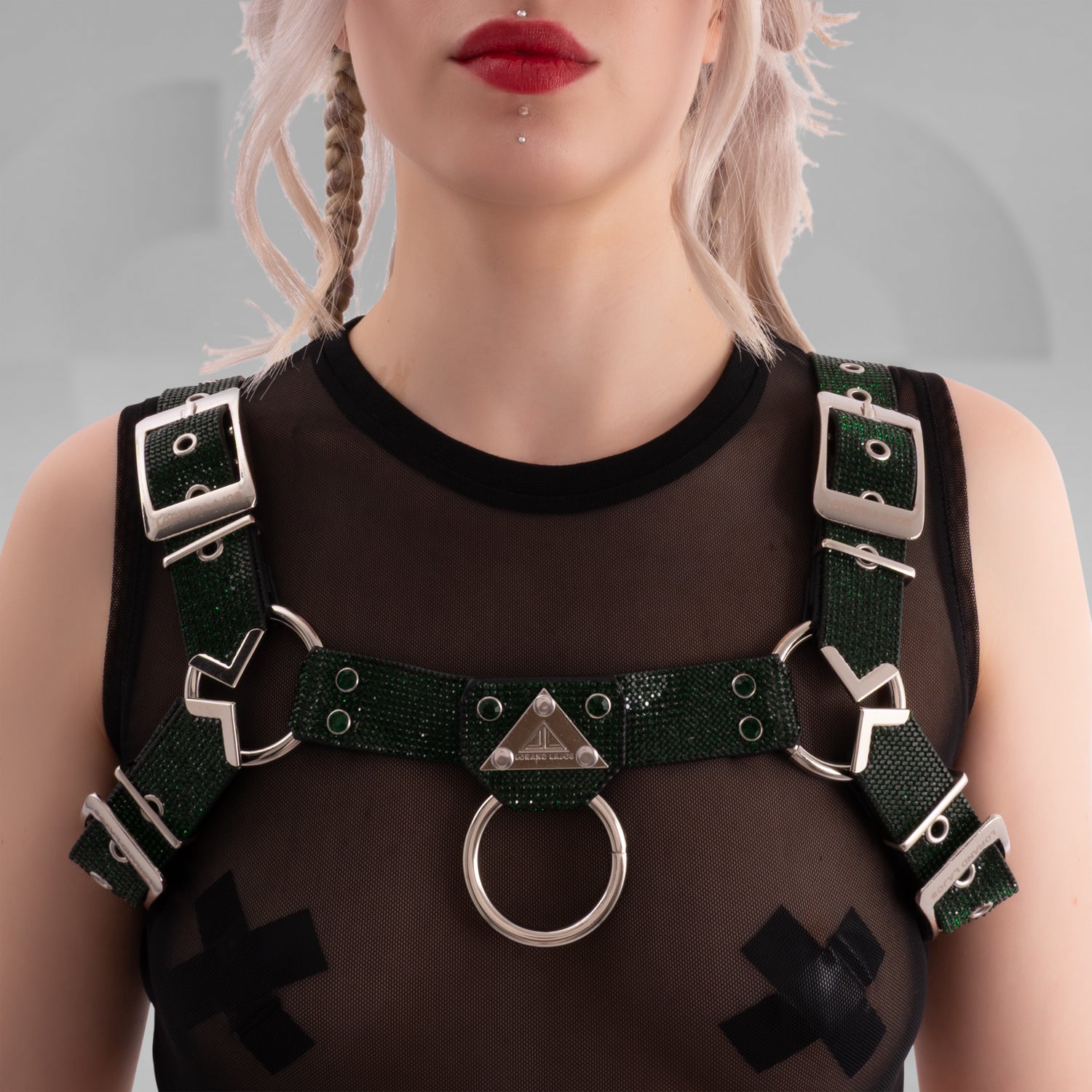 Person wearing a green harness with metal rings on a plain background