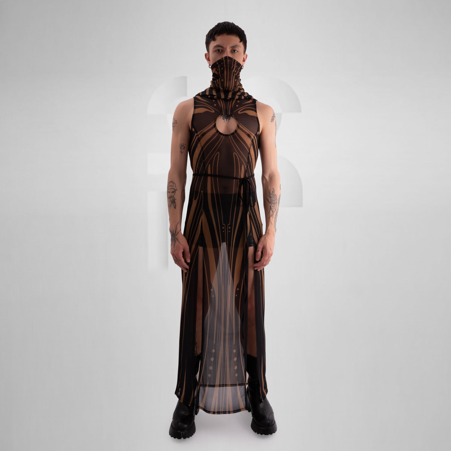 The image showcases a striking, futuristic sheer dress with intricate gold detailing and a matching hood, creating a bold and avant-garde look. 