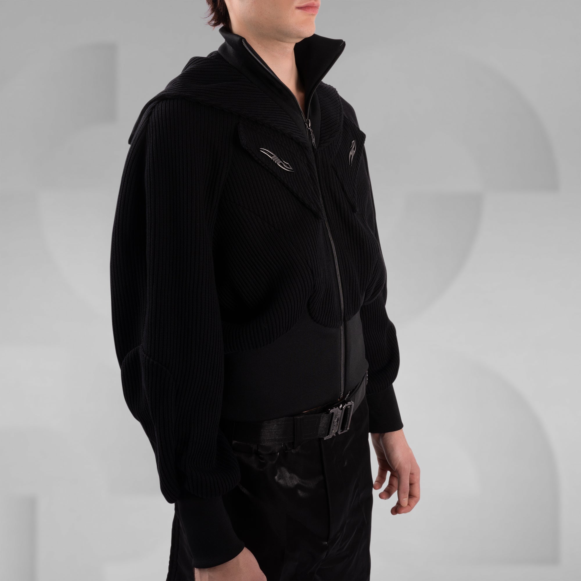 Person wearing a black jacket and pants on a gray background