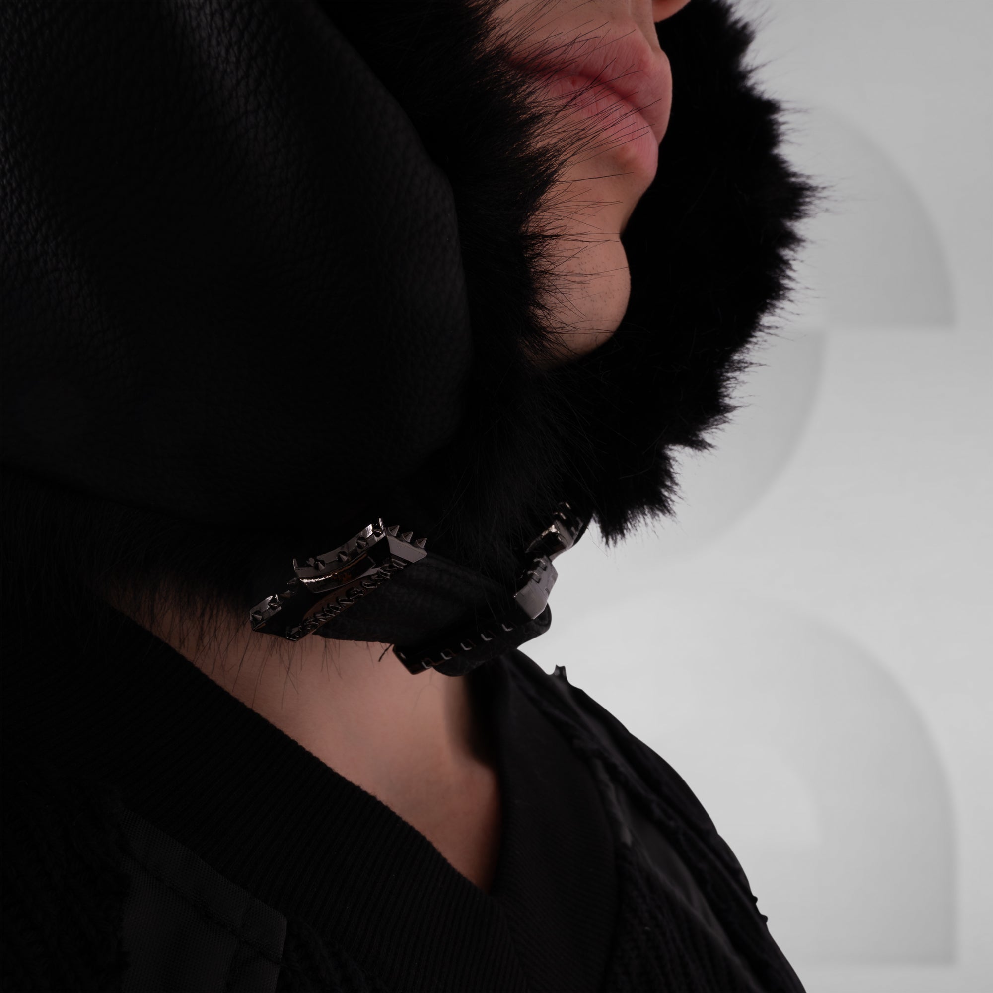 Close-up of a person wearing a black fur-lined hood with a blurred background