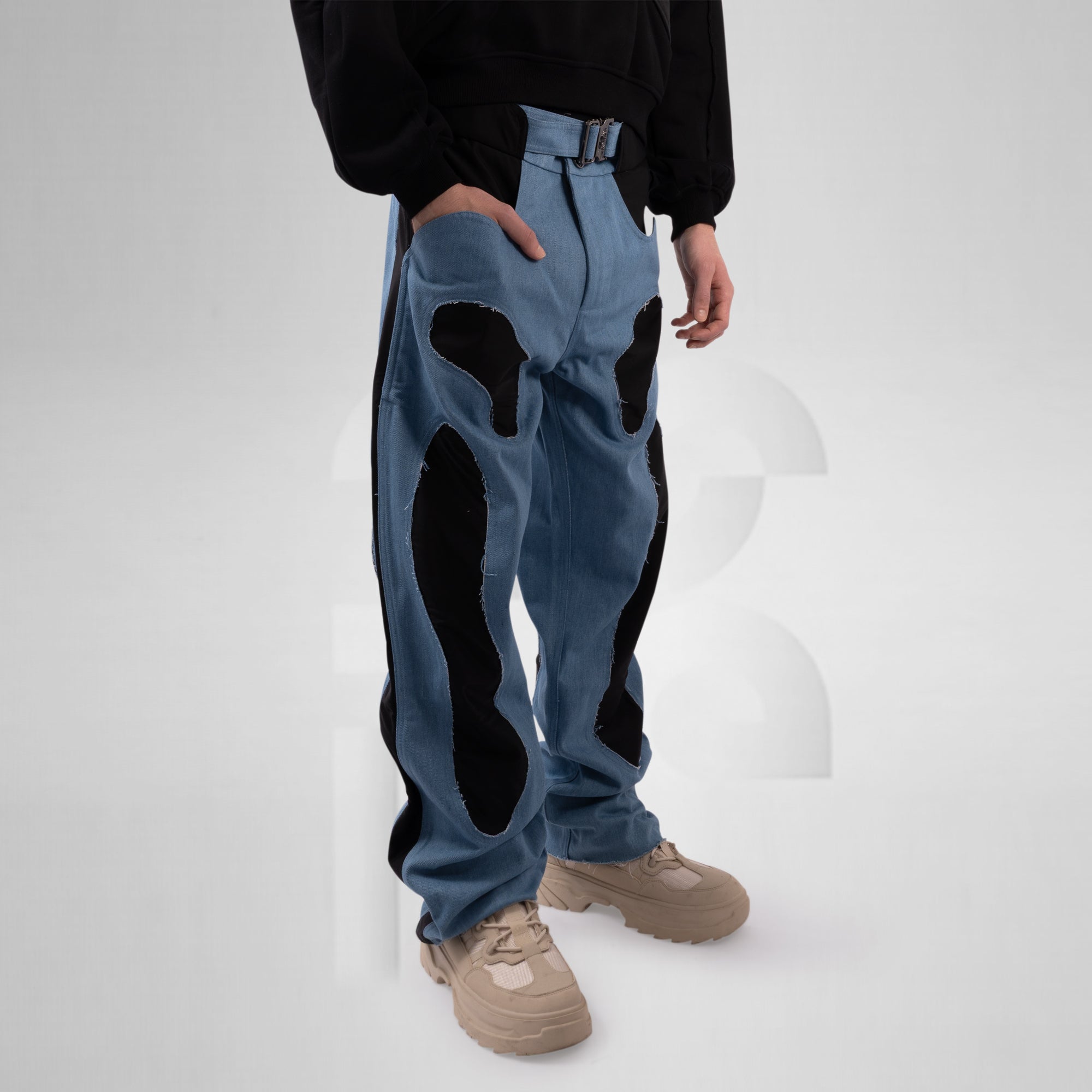 Person wearing blue jeans with black patches on a white background