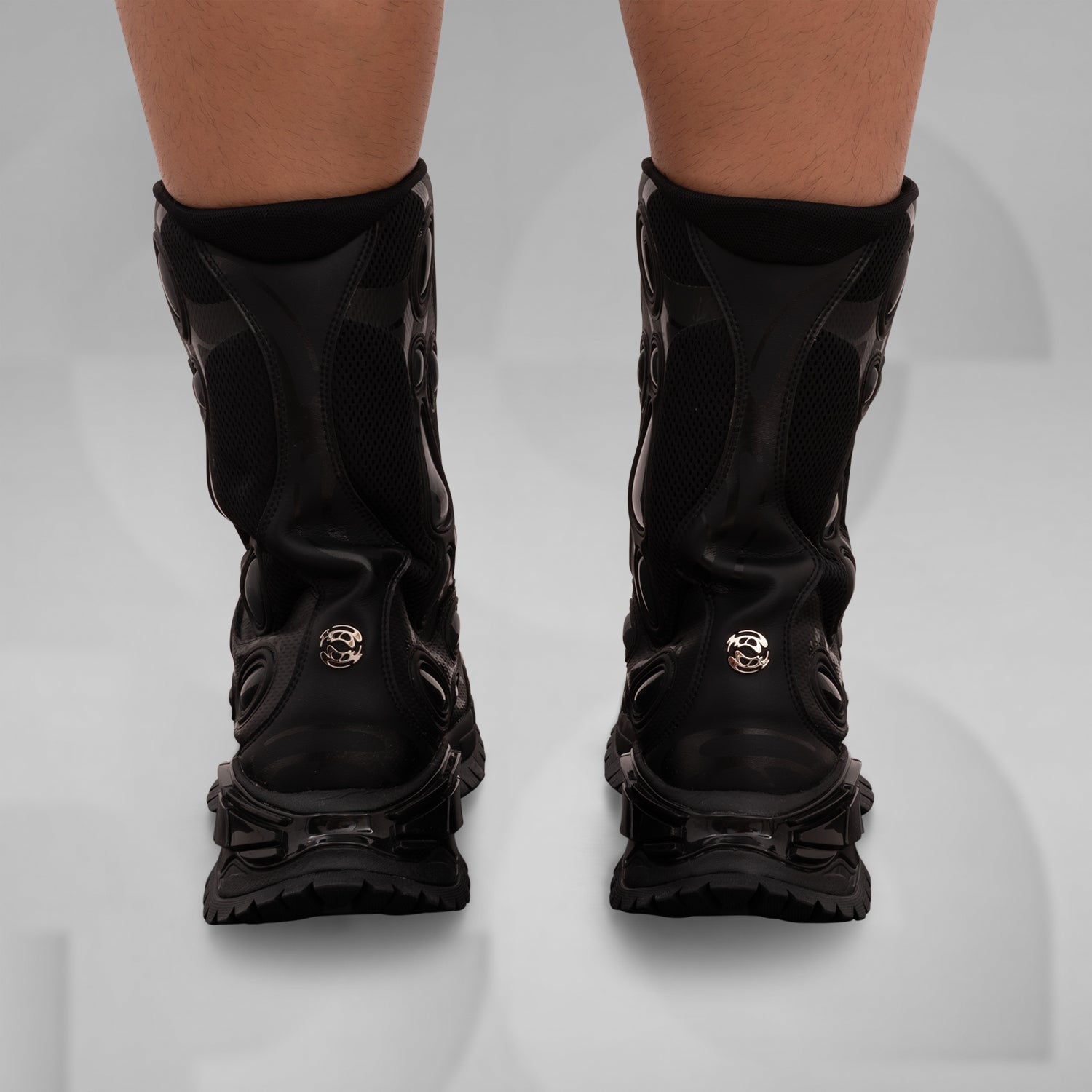 The image features the bold and avant-garde high-top boots from Rombaut, designed for a striking look. These distinctive black boots combine a rugged aesthetic with innovative details, including dynamic lacing and textural contrasts. Ideal for making a statement in any clubwear repertoire, they elevate your style with a perfect blend of functionality and high fashion. Perfect for those who dare to stand out!