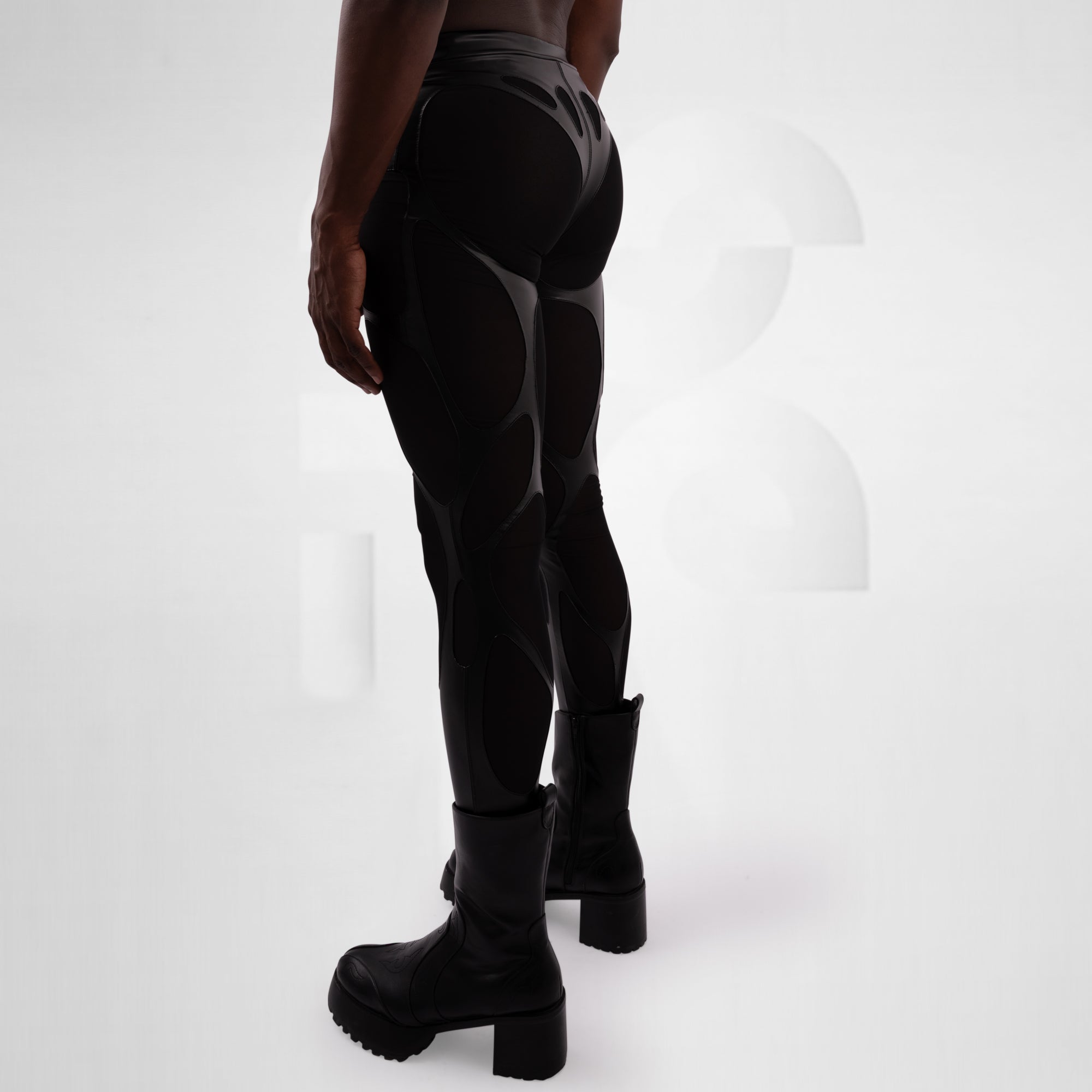 Person wearing black futuristic pants and boots on a white background
