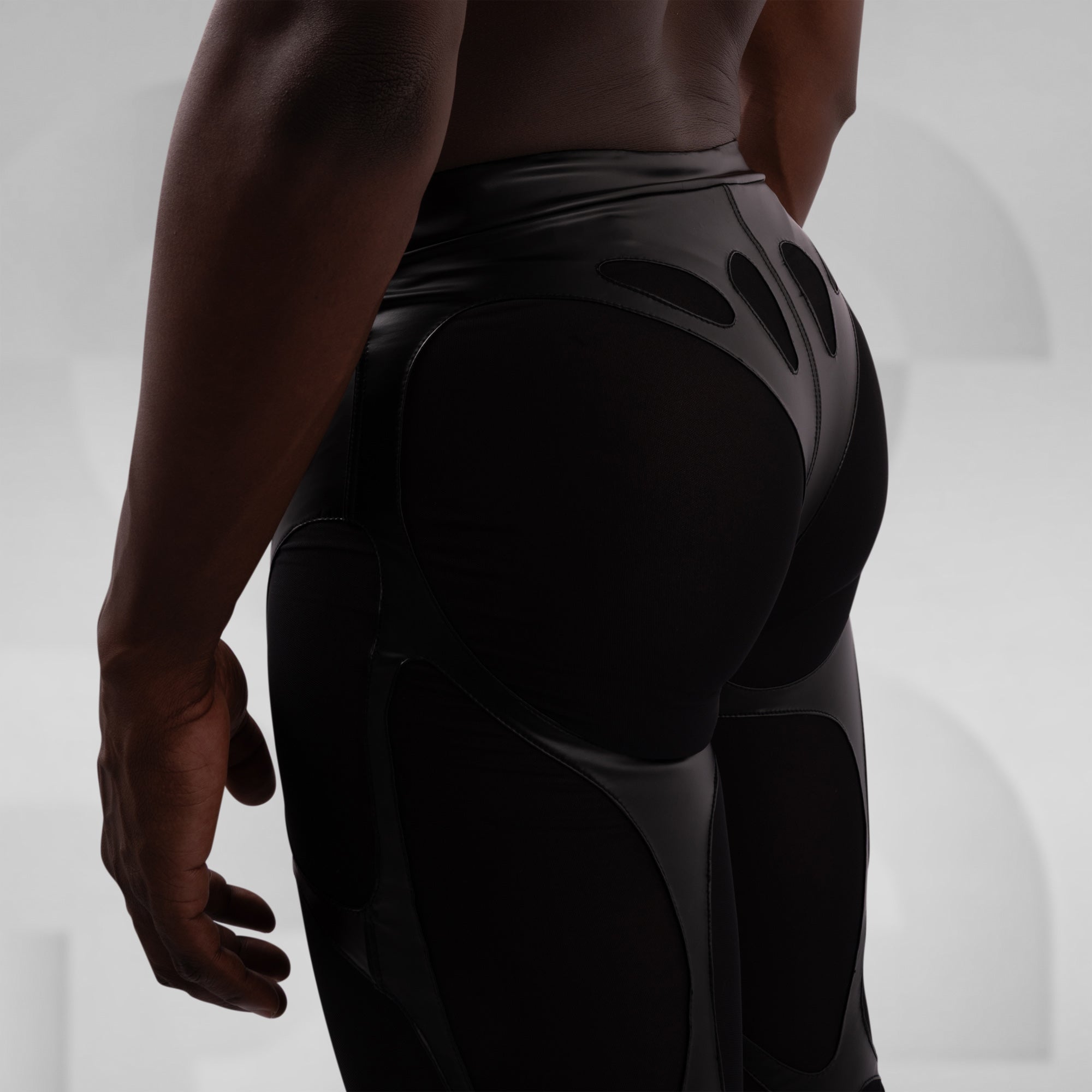 Person wearing black athletic pants on a light gray background