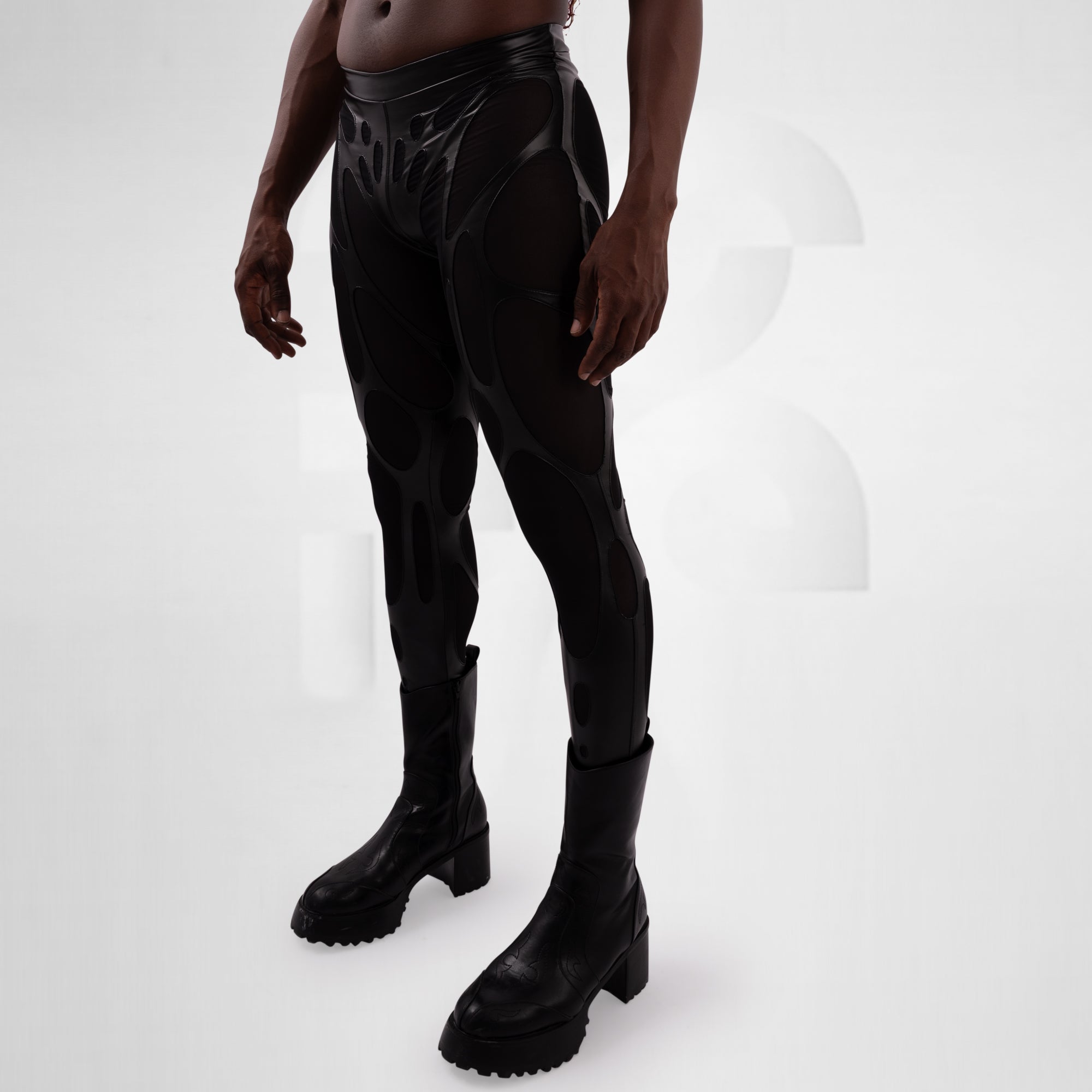Person wearing black vinyl pants and boots on a white background