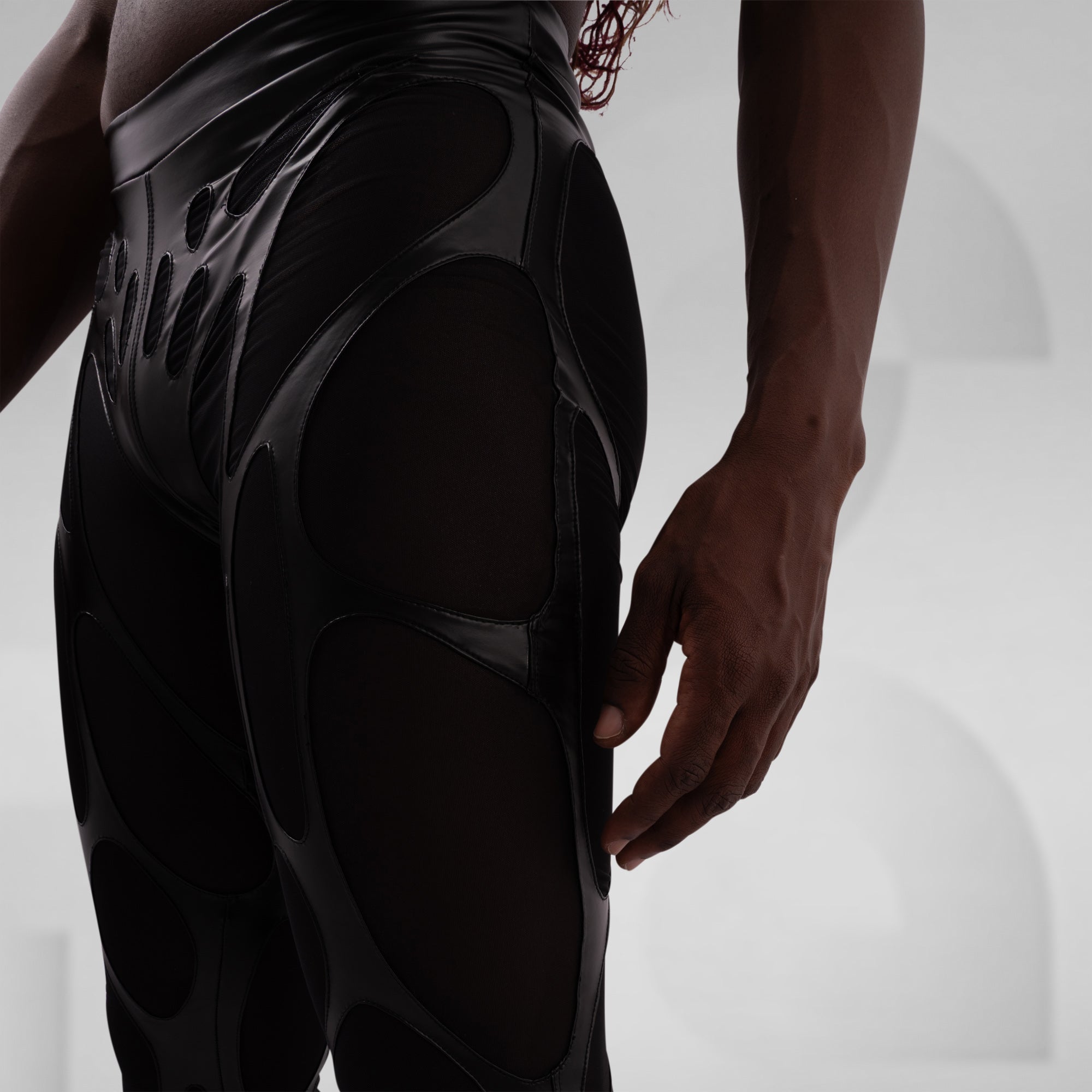 Person wearing a black, futuristic-looking bodysuit on a light gray background