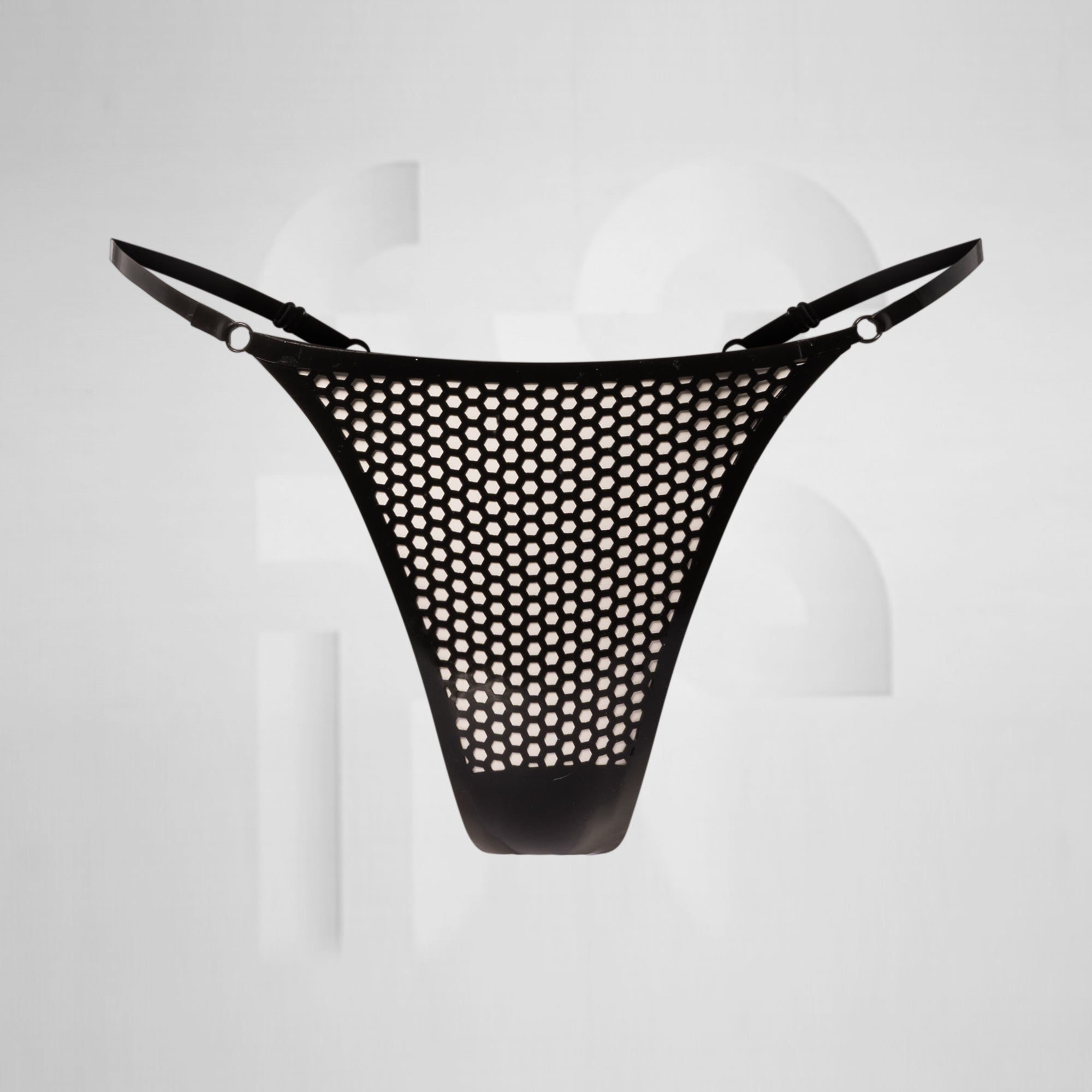 black latex thong in front of grey background