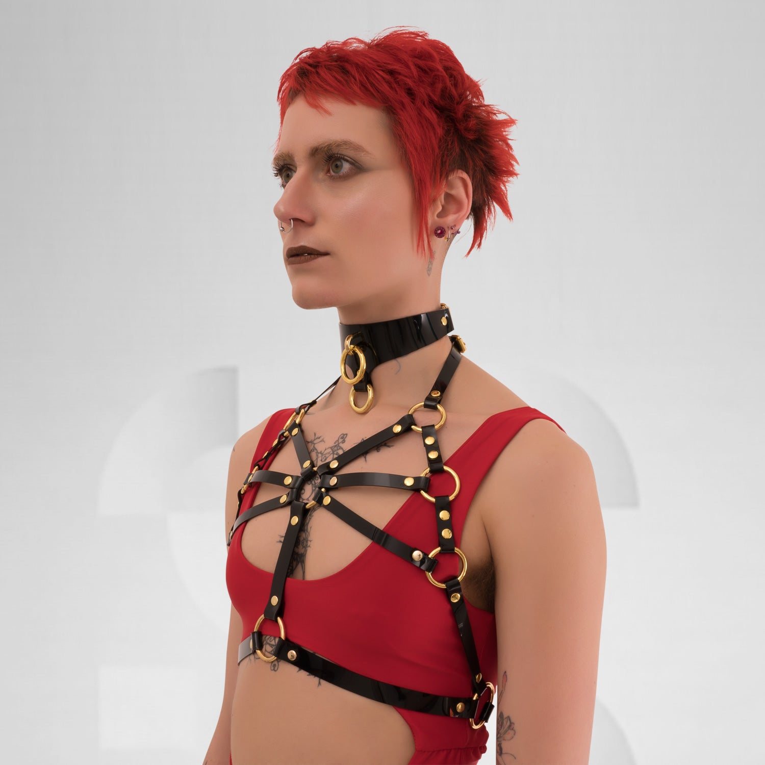  A back view of the Harness Top in Black PVC from Miss Overdose, featuring striking golden or silver rings. This edgy and stylish harness captures a kinky aesthetic, making it ideal for events, techno clubs, or festivals, while also ensuring a comfortable fit.