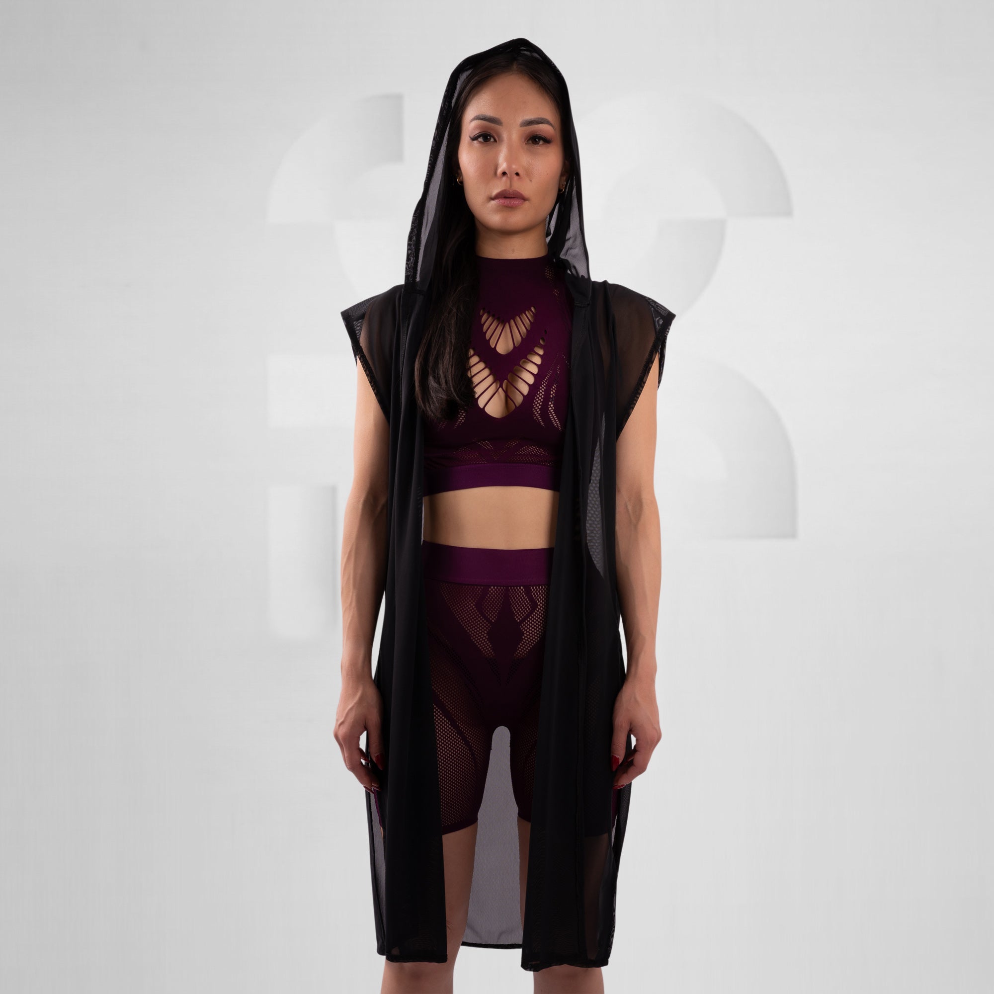 Woman wearing a black and purple outfit with a sheer overlay on a white background