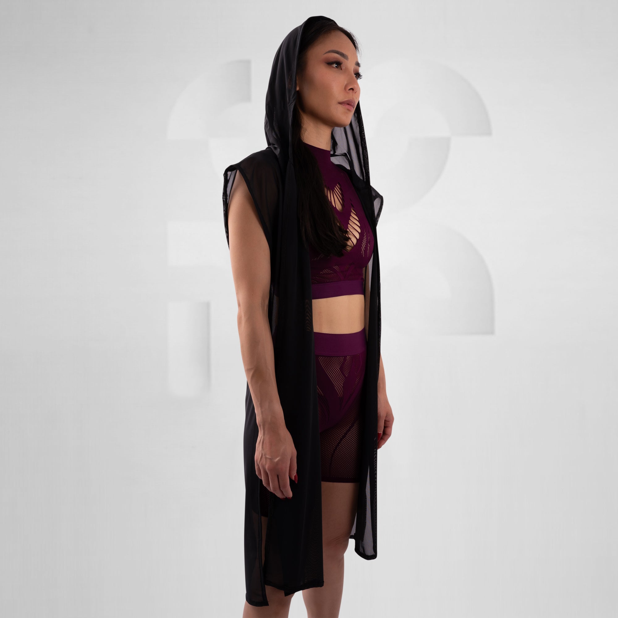 Woman wearing a black and purple outfit with a sheer overlay against a white background