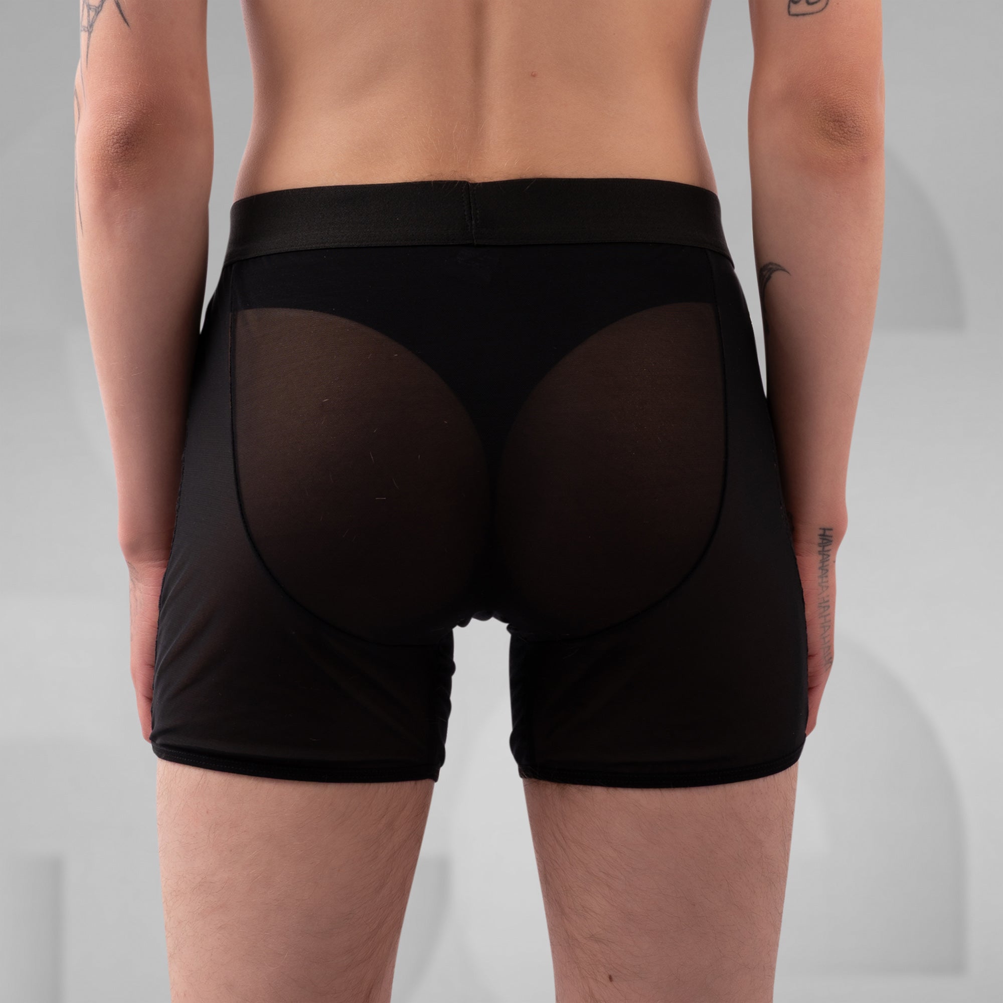 Person wearing black underwear on a plain background