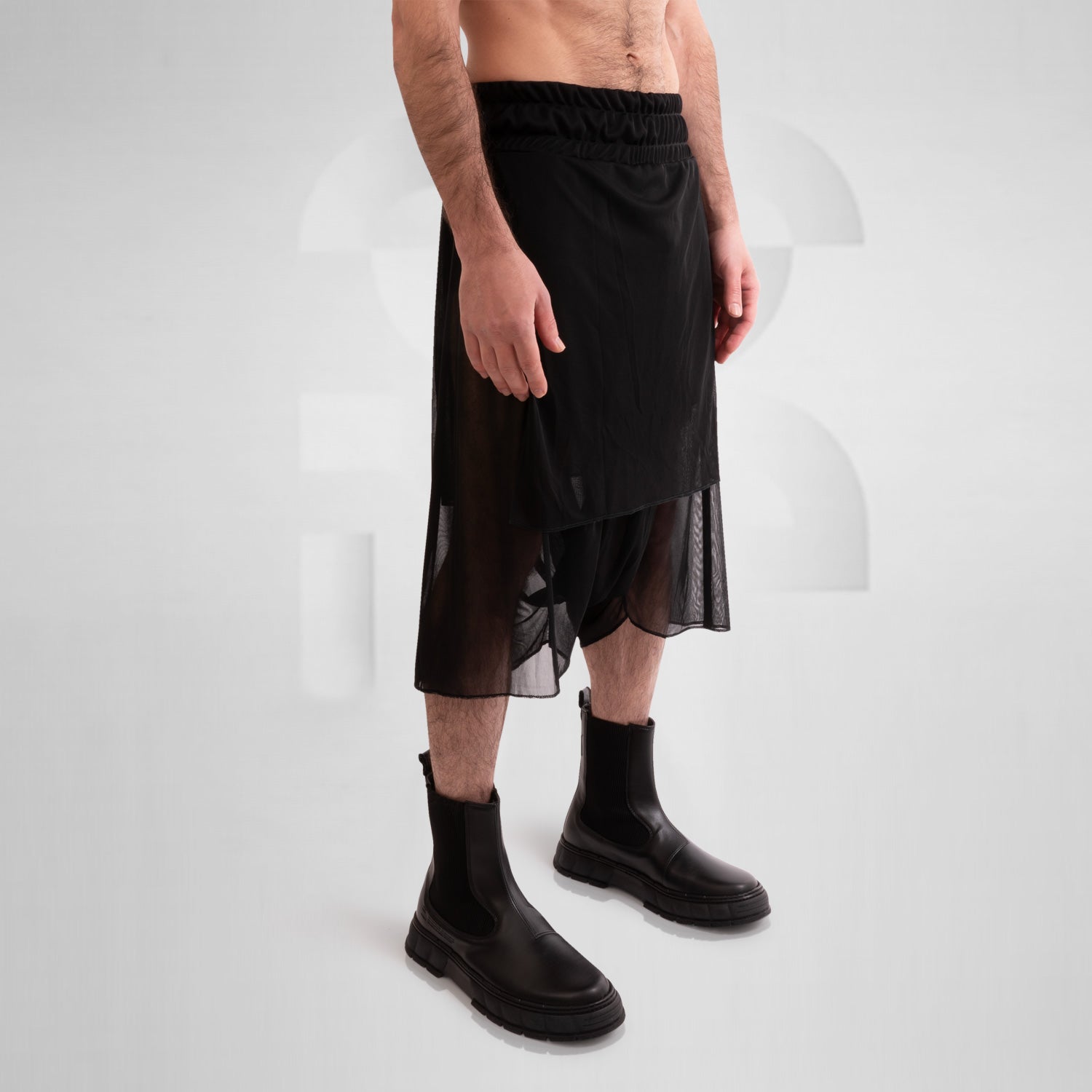 Layered Mesh Shorts from This is Fred featuring a unique layered design made of lightweight mesh, styled with black boots, ideal for avant-garde fashion and versatile wear for club nights and everyday occasions.