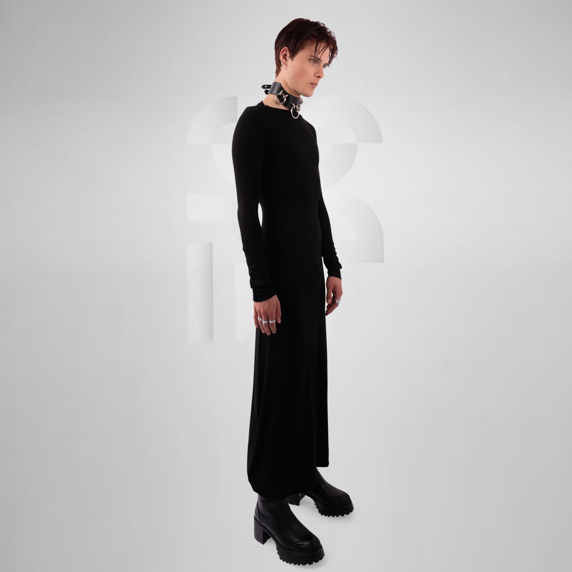 Person wearing a long black dress with platform shoes on a white background