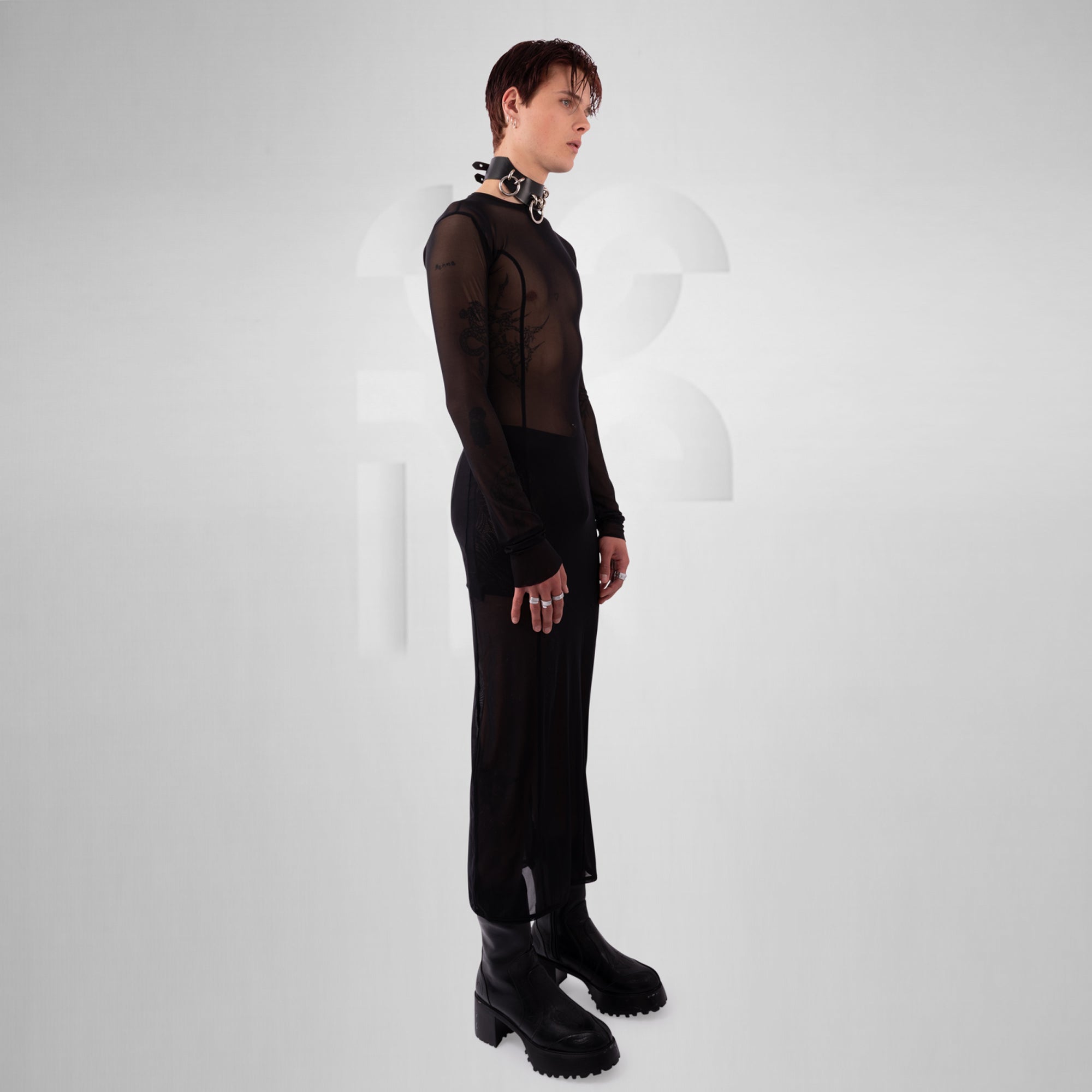 Person wearing a black outfit with sheer sleeves on a white background