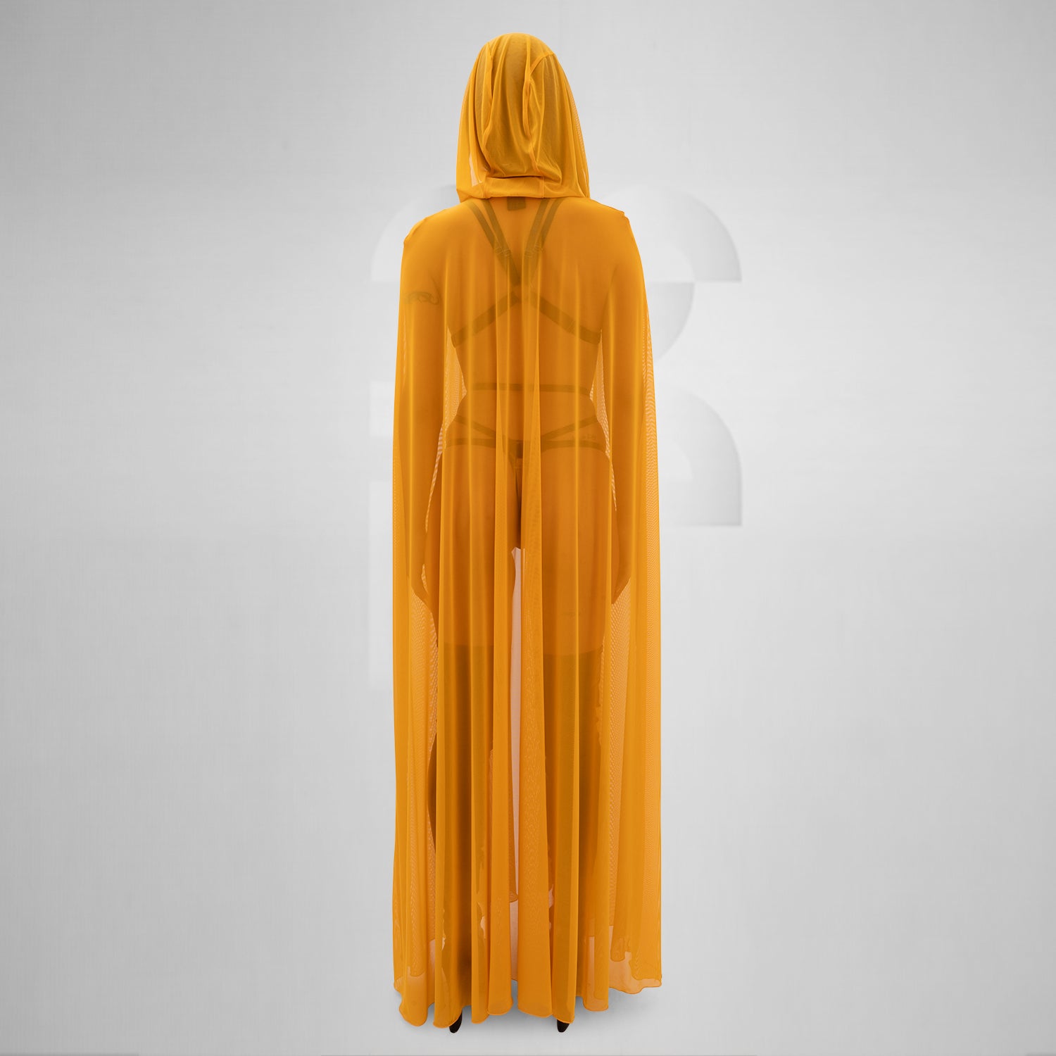 The image features a person wearing a flowing, sheer yellow cape that drapes elegantly to the floor. The cape is lightweight and creates a striking, dramatic silhouette. Underneath, the person is styled in minimal, edgy fashion, with strappy details adding a touch of avant-garde flair. The combination of the vibrant yellow cape and bold styling elements makes for a standout look that’s perfect for fashion-forward occasions.