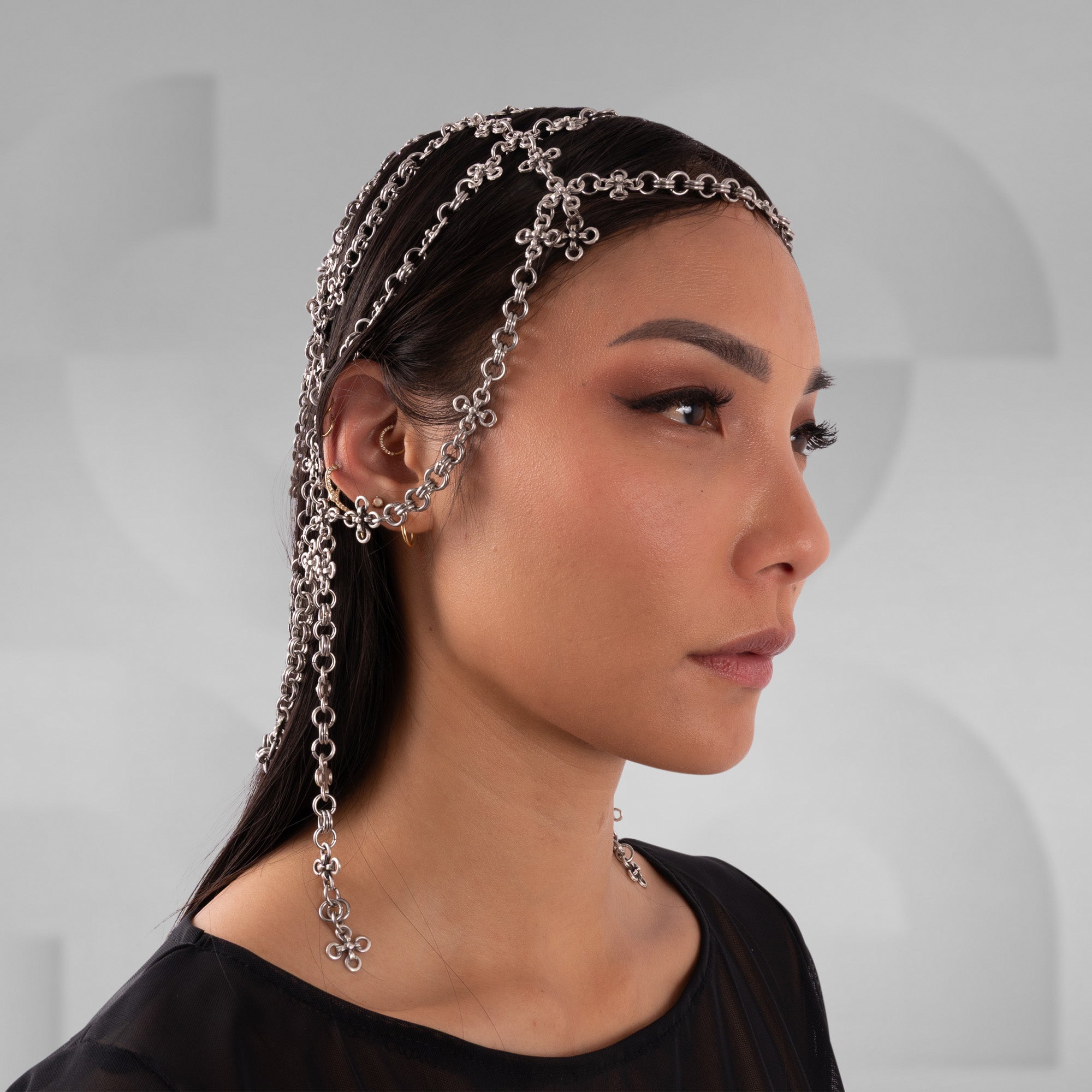 Woman wearing a chain headband with a neutral background