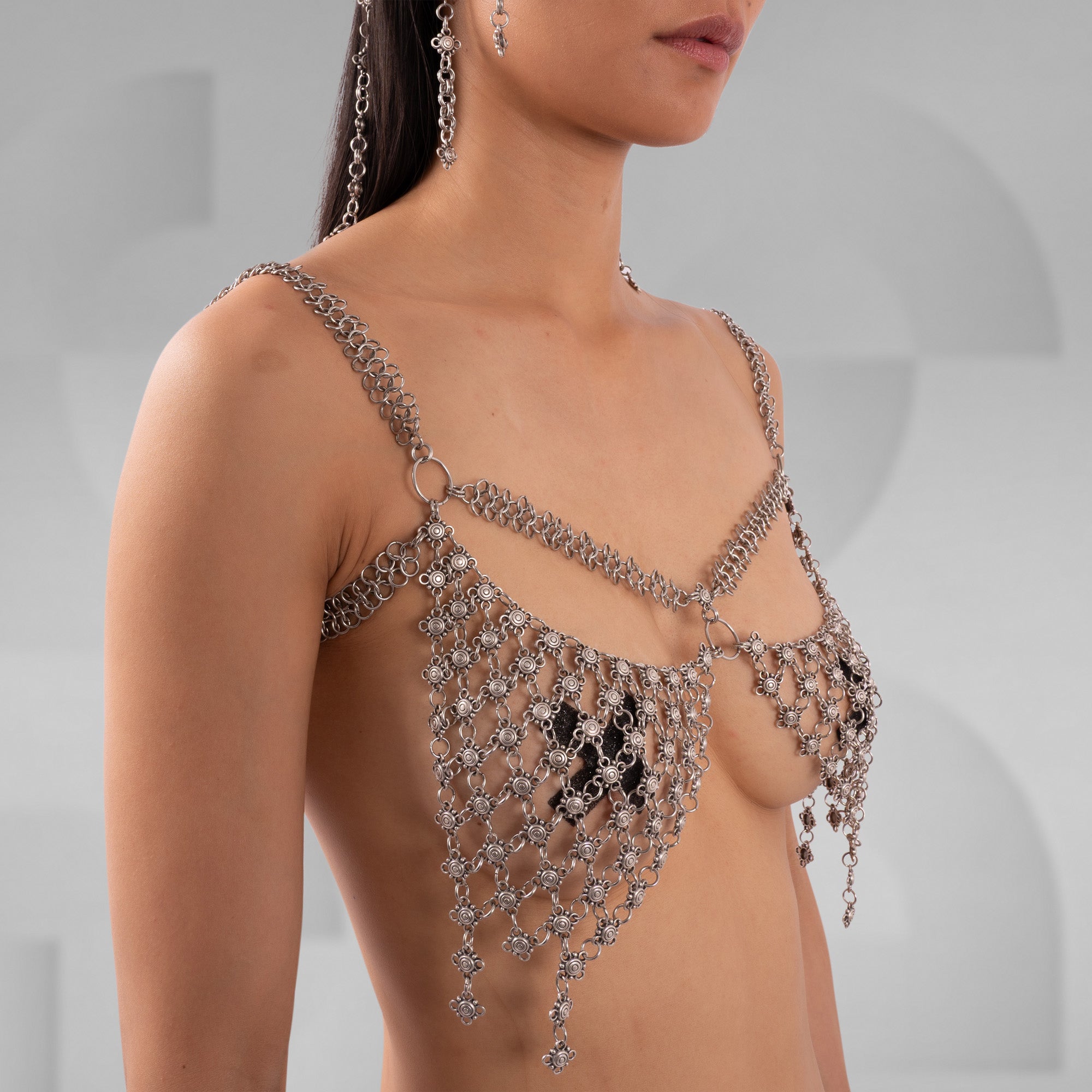 Close-up of a person wearing a sparkling chain and gemstone top against a neutral background