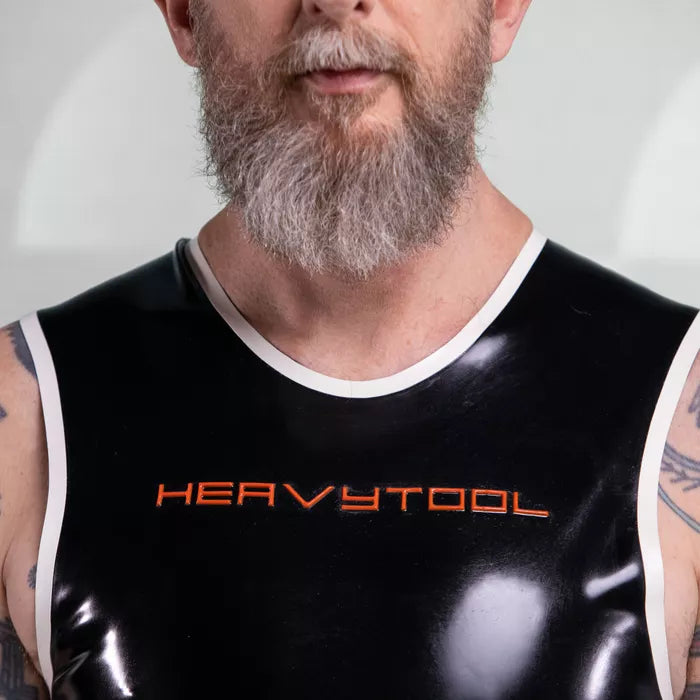 The image features a striking outfit from HeavyTool Gear, showcasing a sleek black sleeveless top with matching shorts. Crafted from glossy latex, this ensemble hugs the body for a flattering fit, complete with a bold logo on the waistband. Perfect for the party scene, it combines edgy style with comfort, making it an ideal choice for anyone looking to make a statement while embracing their individuality.